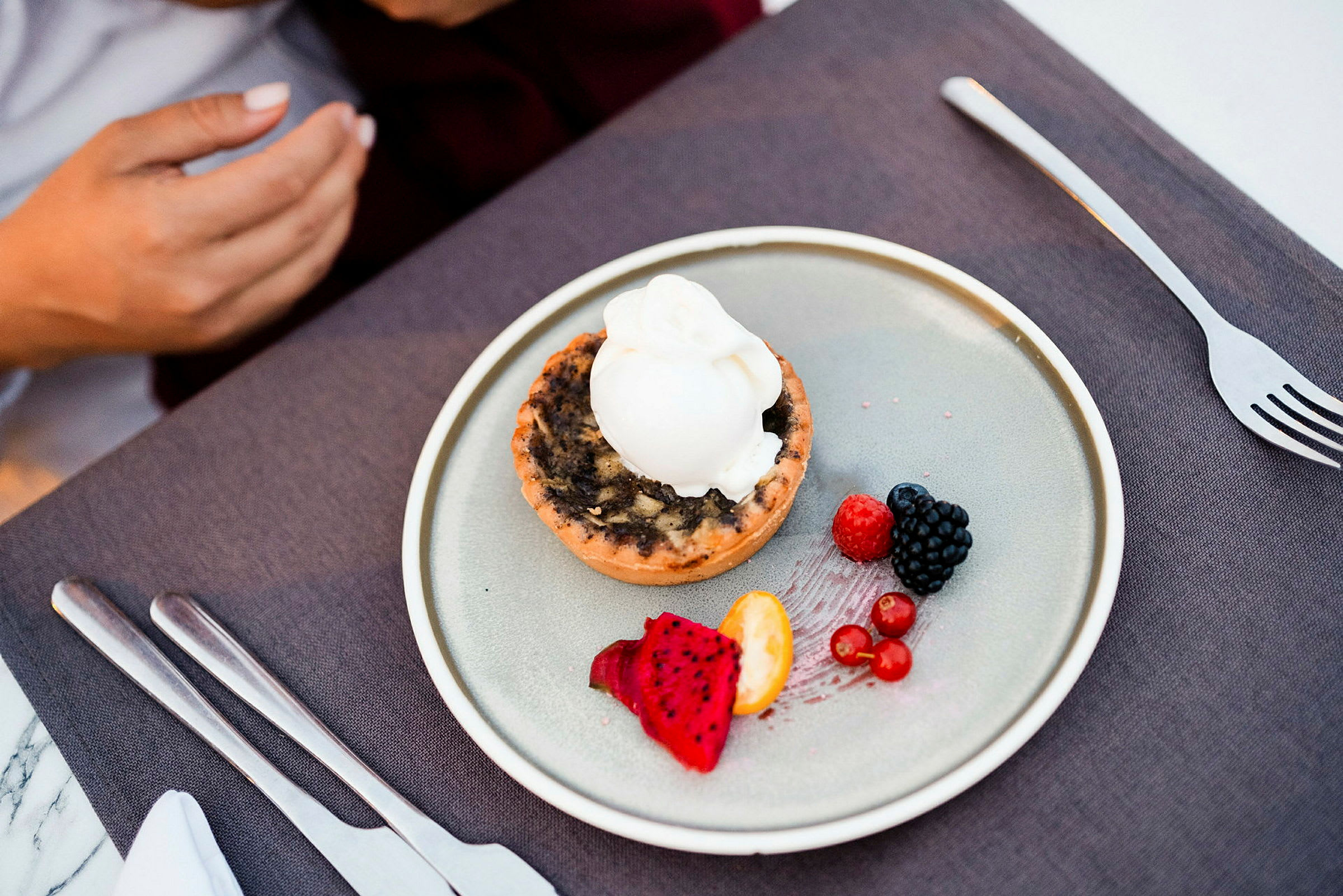 En dessert på en tallerken, der inkluderer en tærte med is og forskellige frugter. (AI-genereret tekst)