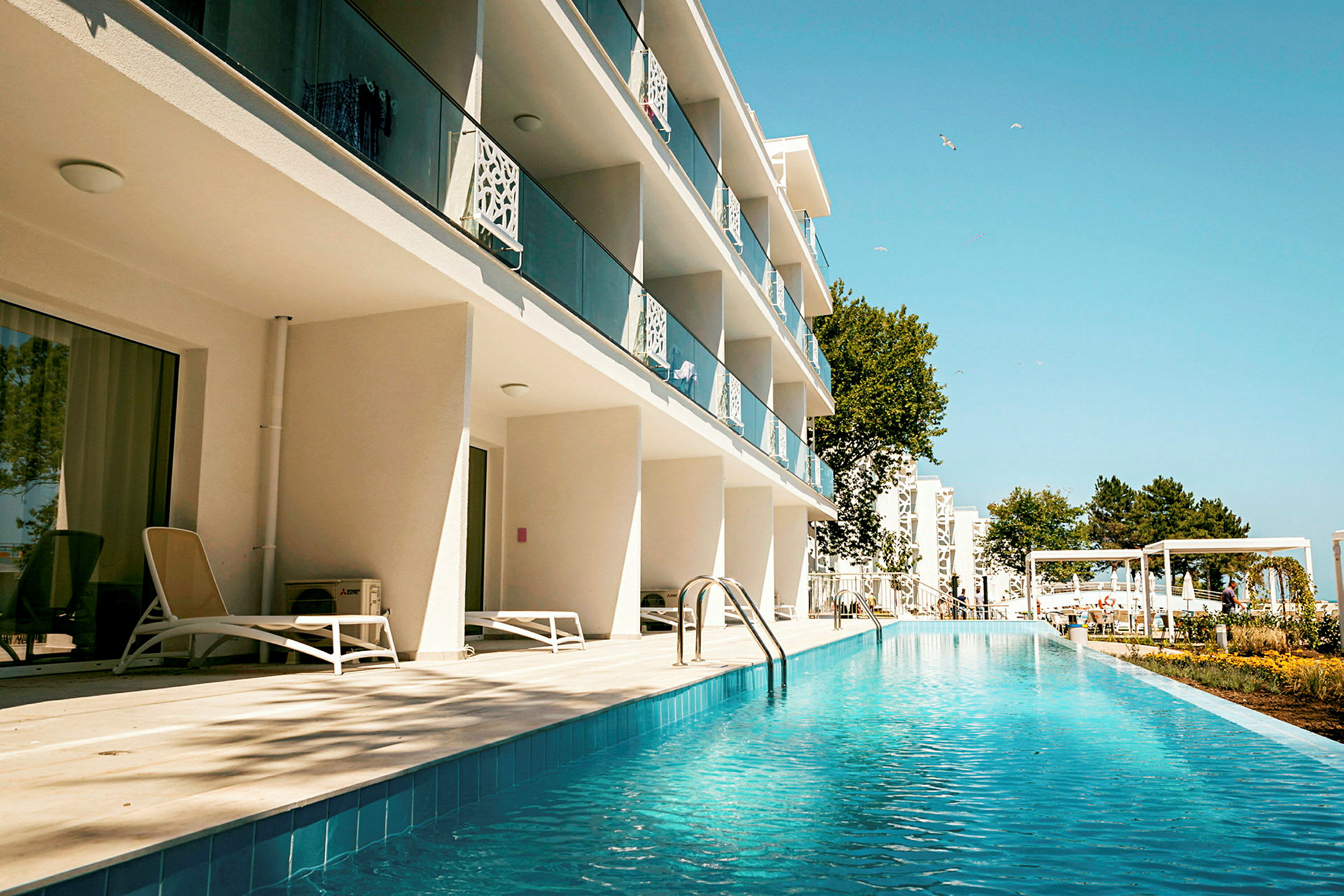 Hotelbygning med altaner og poolområde. (AI-genereret tekst)
