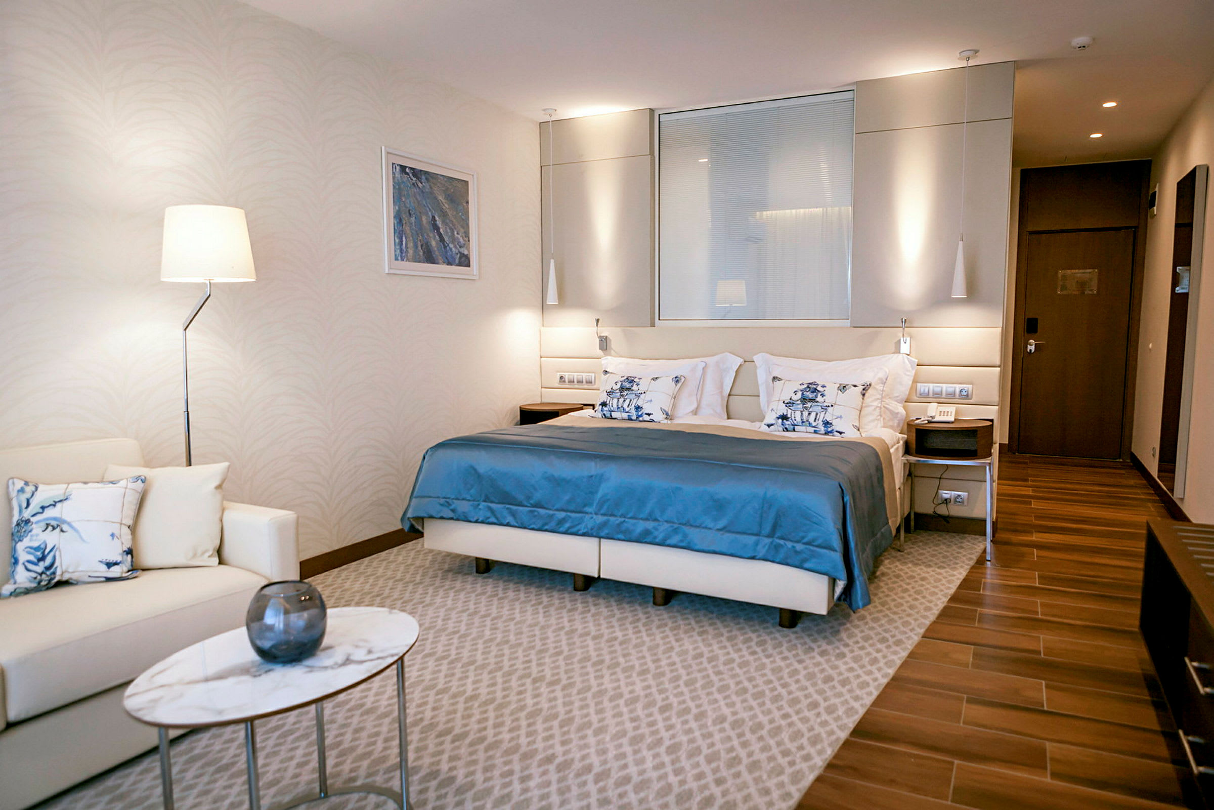 Et moderne hotelværelse med en dobbeltseng, en siddegruppe og et lille marmorbord. (AI-genereret tekst)