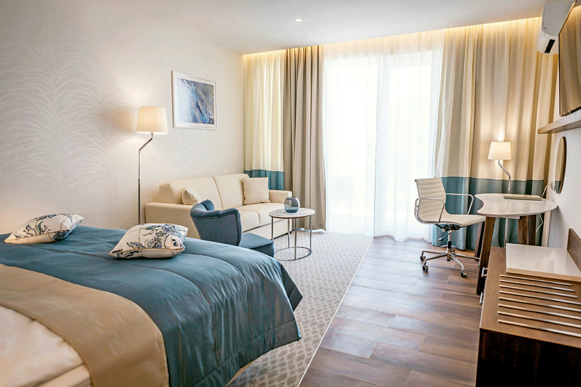 Et hotelværelse med en seng, sofa, bord og skrivebord med stol. (AI-genereret tekst)