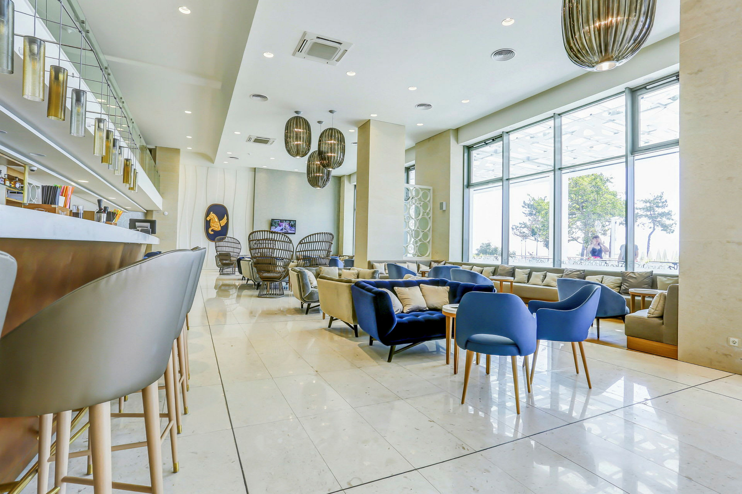 En moderne lounge med stole og sofaer foran store vinduer. (AI-genereret tekst)