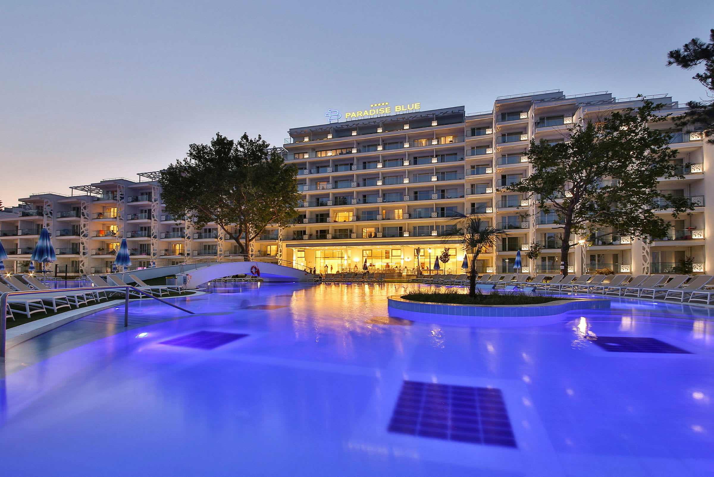 Et oplyst hotel ved en pool om aftenen. (AI-genereret tekst)