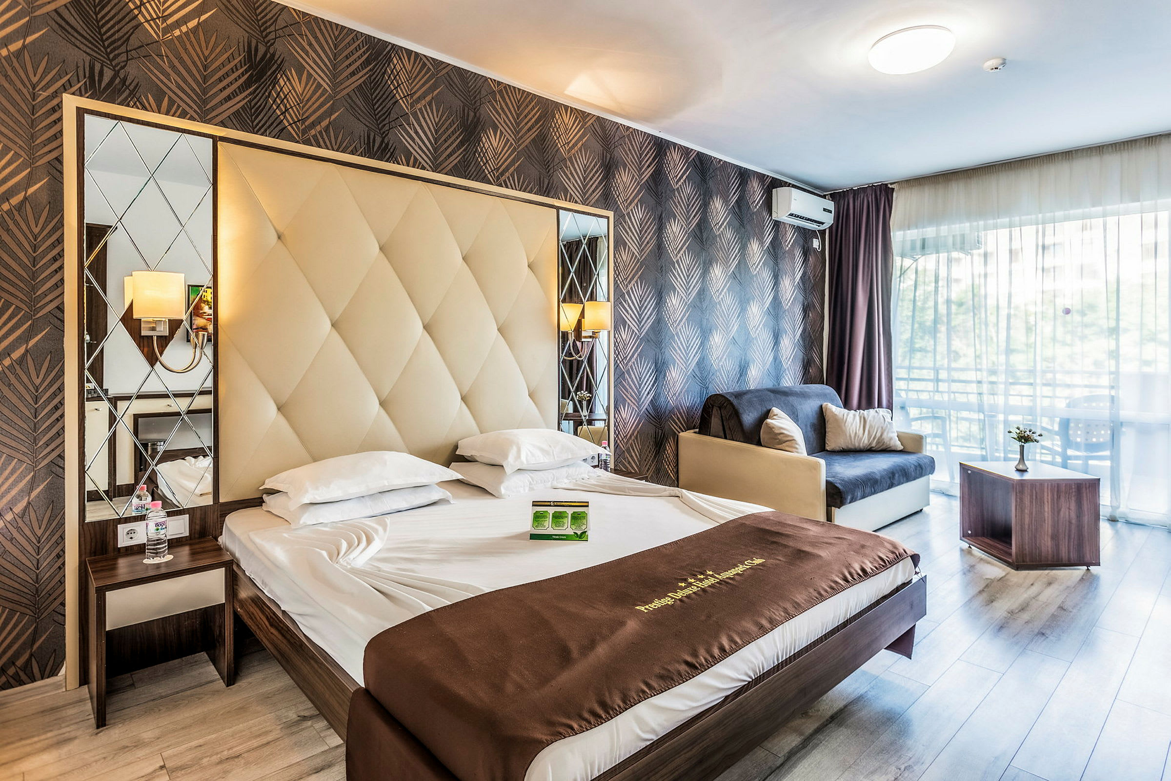 Et hotelværelse med en dobbeltseng, en sofa og et bord. Værelset har en moderne indretning med pæne mønstrede vægge. (AI-genereret tekst)