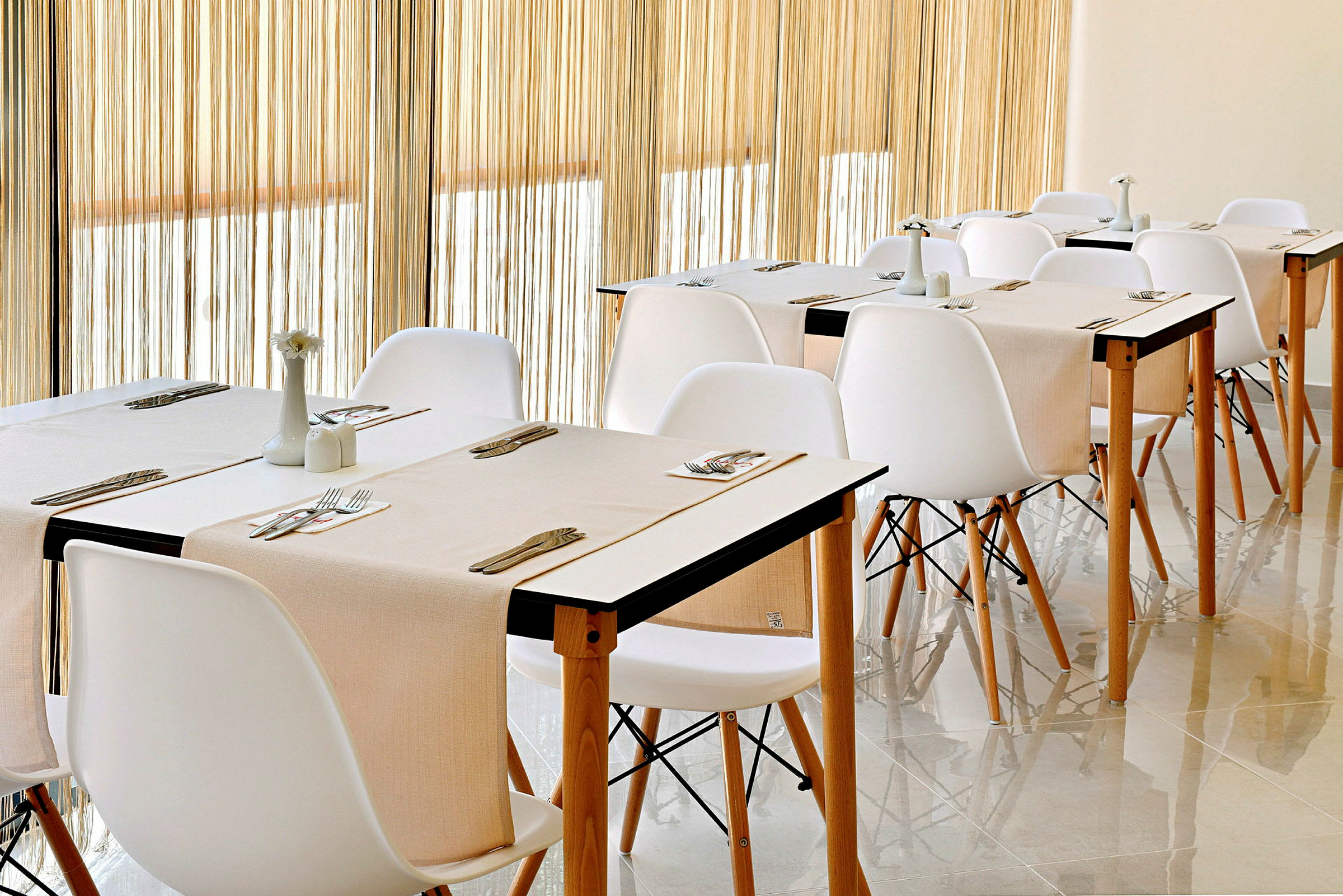 En restaurant med hvide stole og borde med beige duge. (AI-genereret tekst)