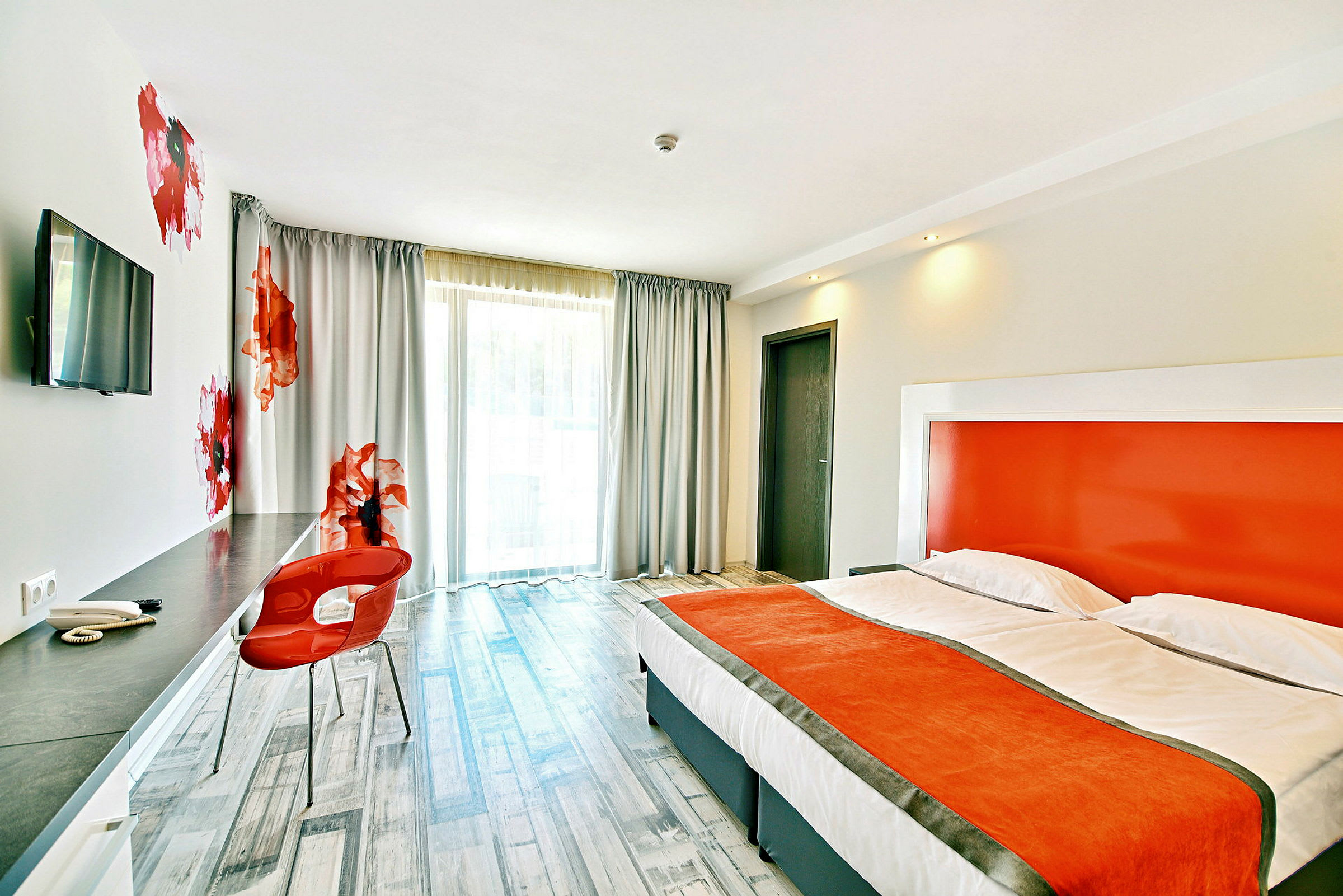 Moderne hotelværelse med orange detaljer, komfortabel seng og skrivebordsområde. (AI-genereret tekst)