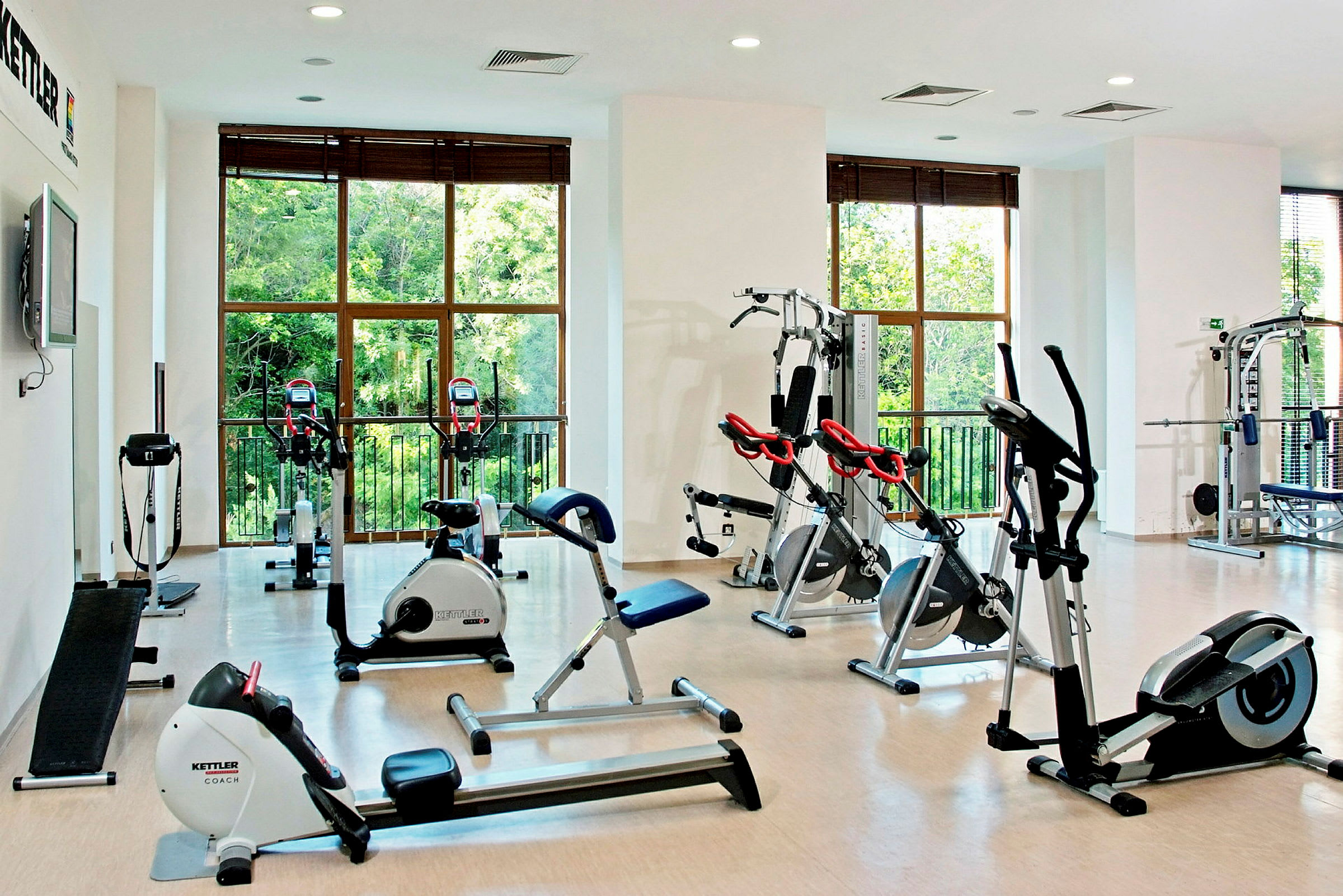 Et fitnesscenter med træningsudstyr og store vinduer. (AI-genereret tekst)