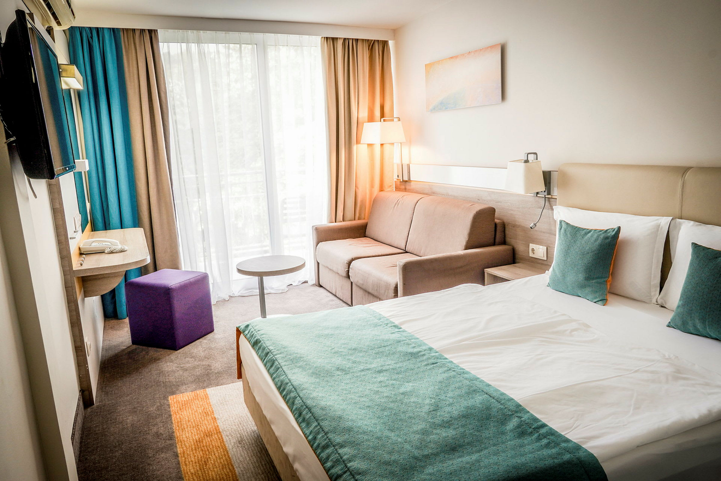 Et moderne hotelværelse med en dobbeltseng, sofa og vindue med gardiner. (AI-genereret tekst)