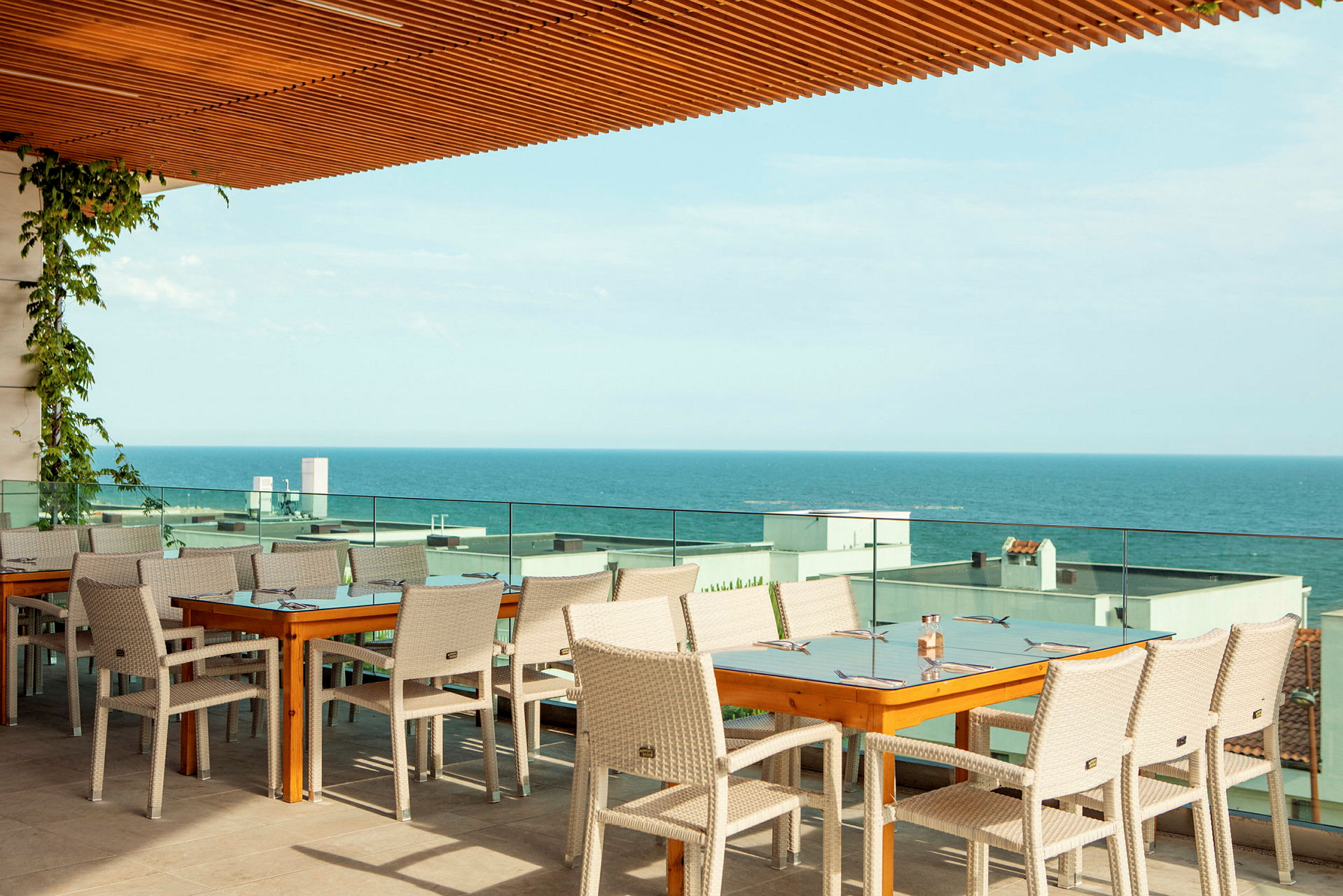 Restaurantborde og stole på en terrasse med udsigt over havet. (AI-genereret tekst)