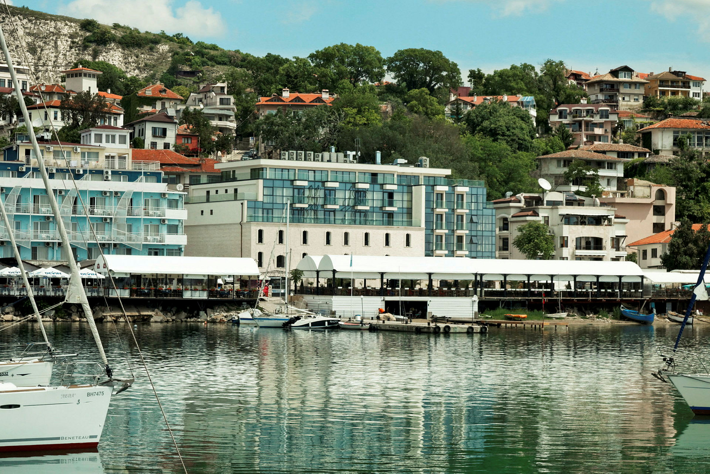 Billede af en havn med både og bygninger i baggrunden. (AI-genereret tekst)