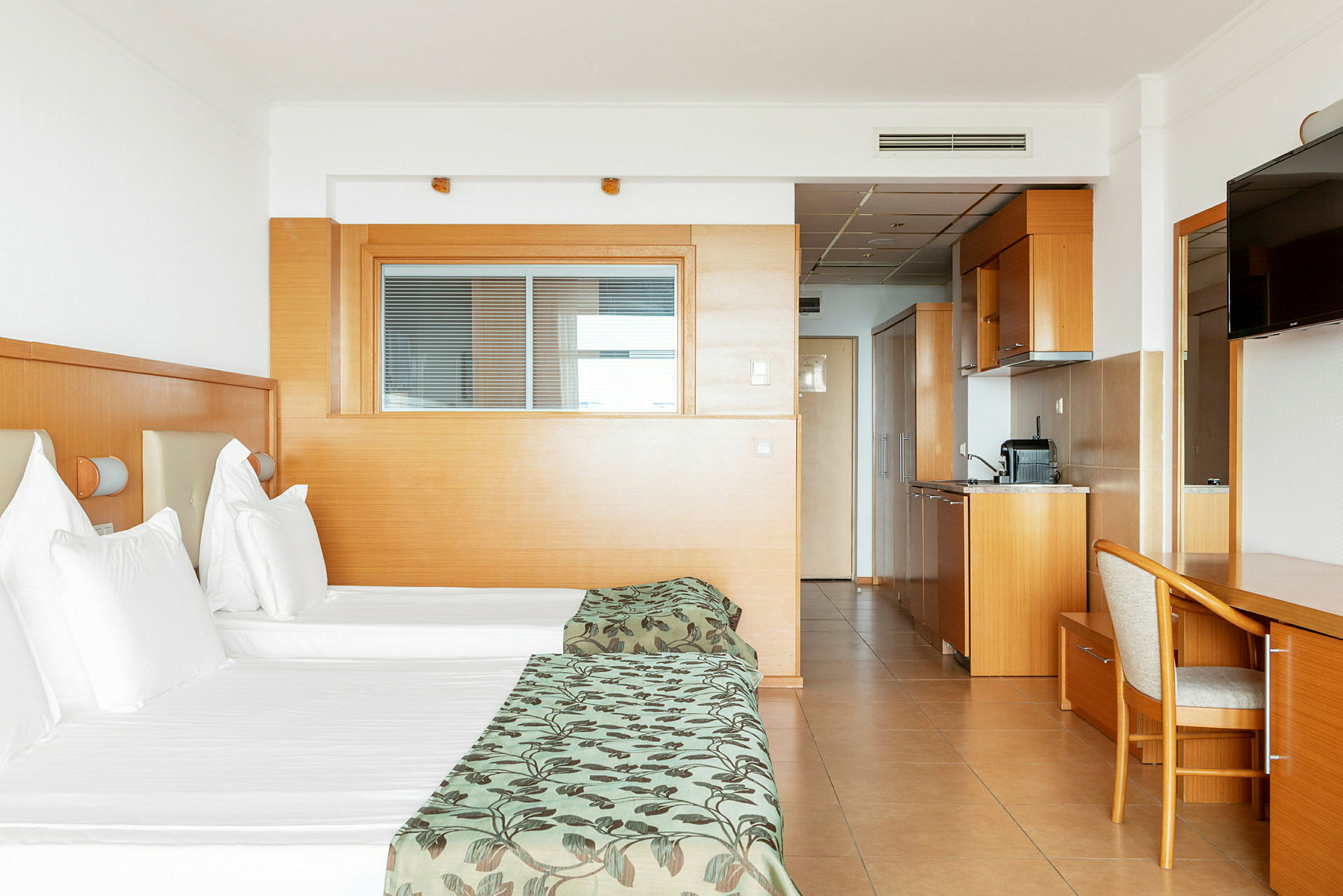 Hotelværelse med to enkeltsenge, tekøkken og skrivebord. (AI-genereret tekst)