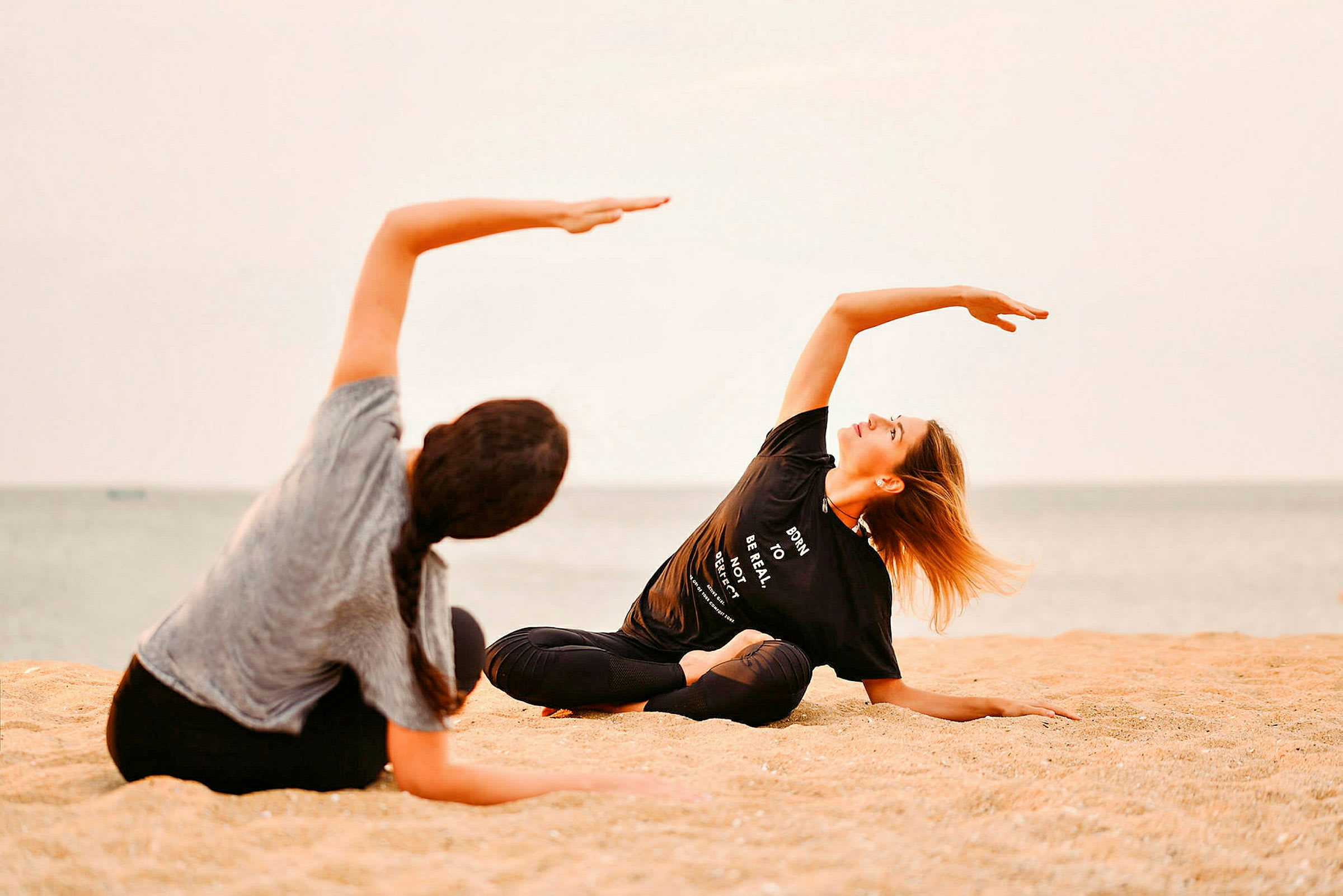 To personer dyrker yoga på en strand. (AI-genereret tekst)