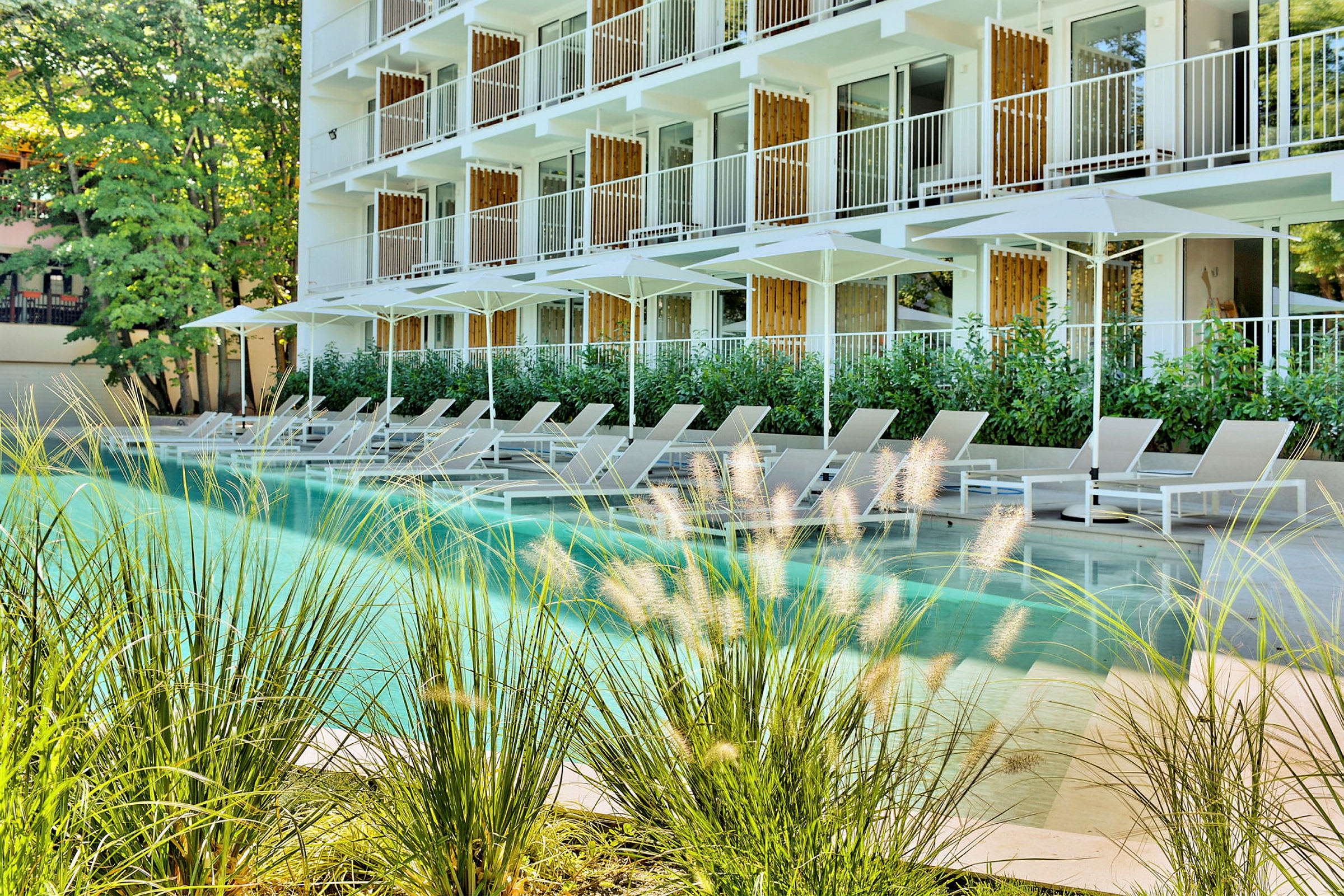 Udendørsområde af hotel med moderne altaner samt liggestole ved en pool. (AI-genereret tekst)