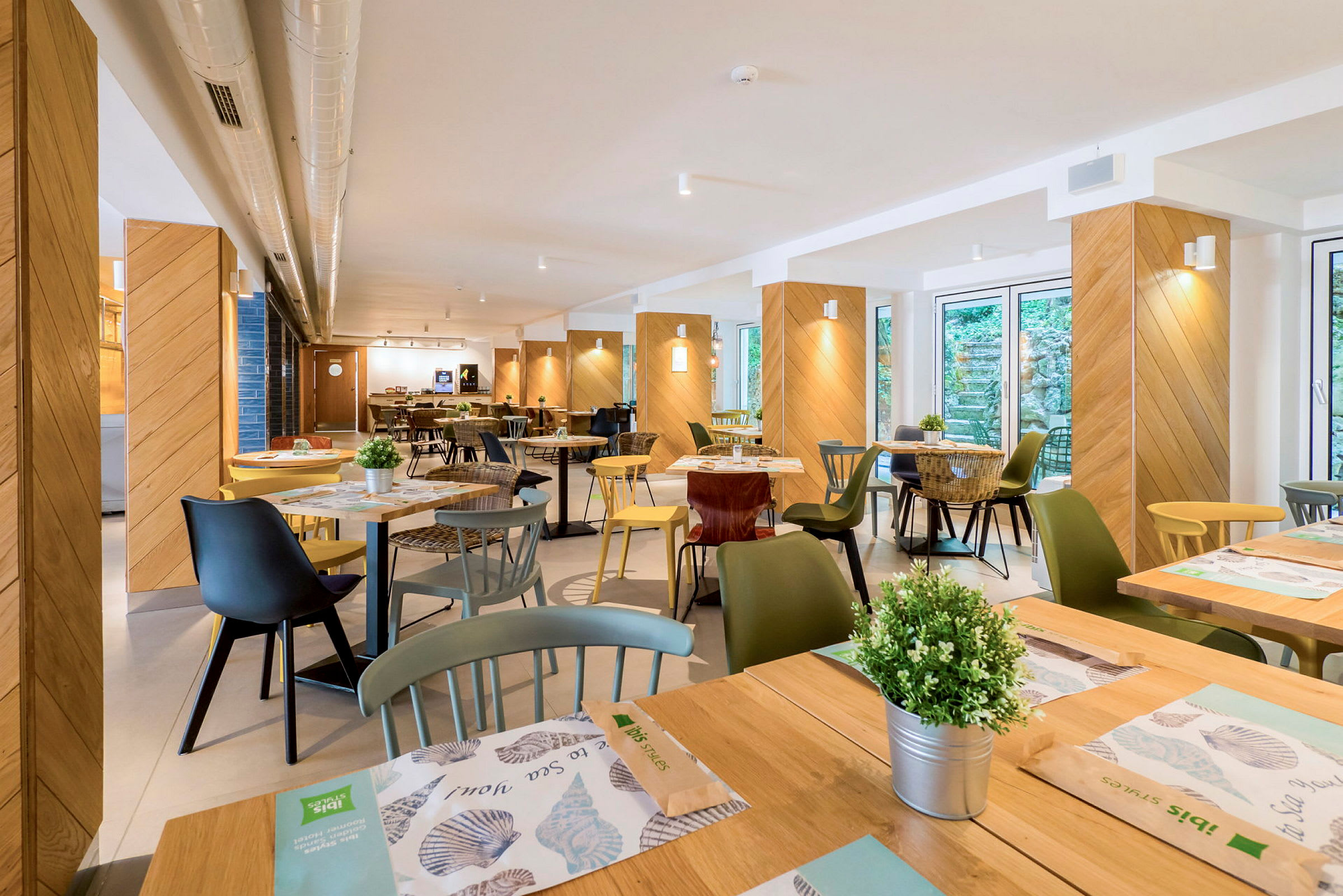 Billede af en restaurant med borde, stole og dekorationer. (AI-genereret tekst)