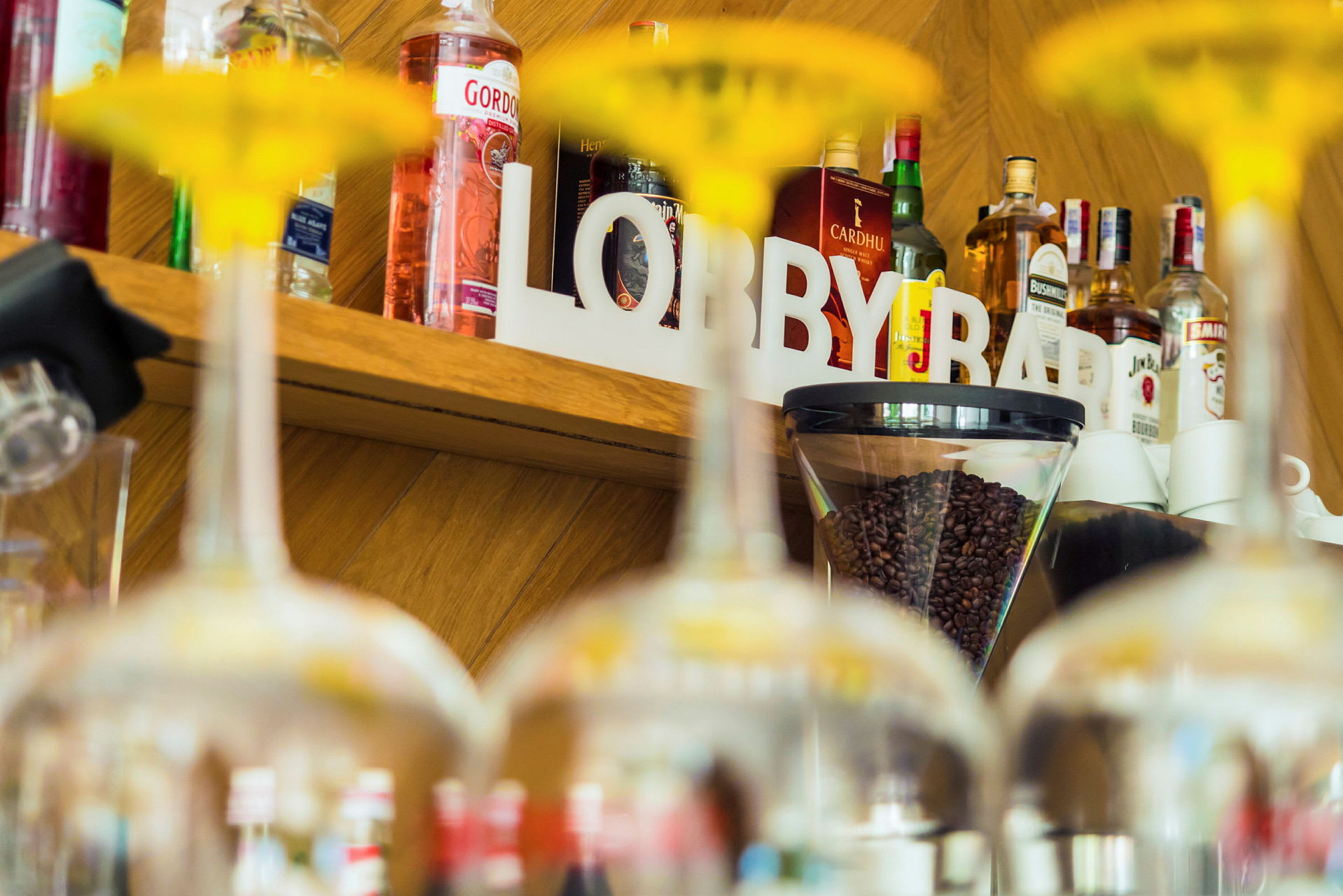 En hylde med flasker, kaffebønner og teksten 'LOBBY BAR' ses bag glas. (AI-genereret tekst)