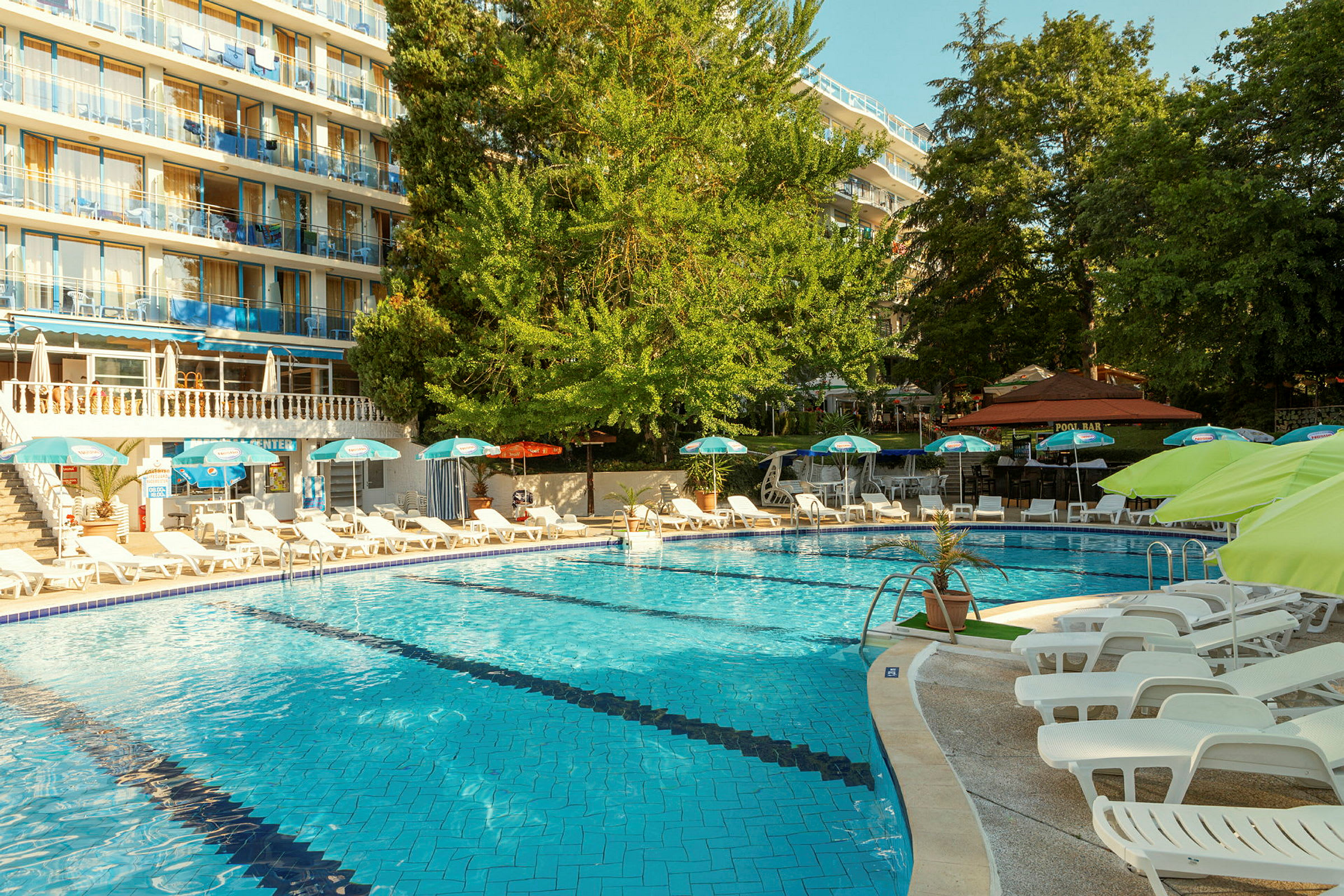 Udendørs swimmingpool med liggestole og parasoller ved et hotel. (AI-genereret tekst)