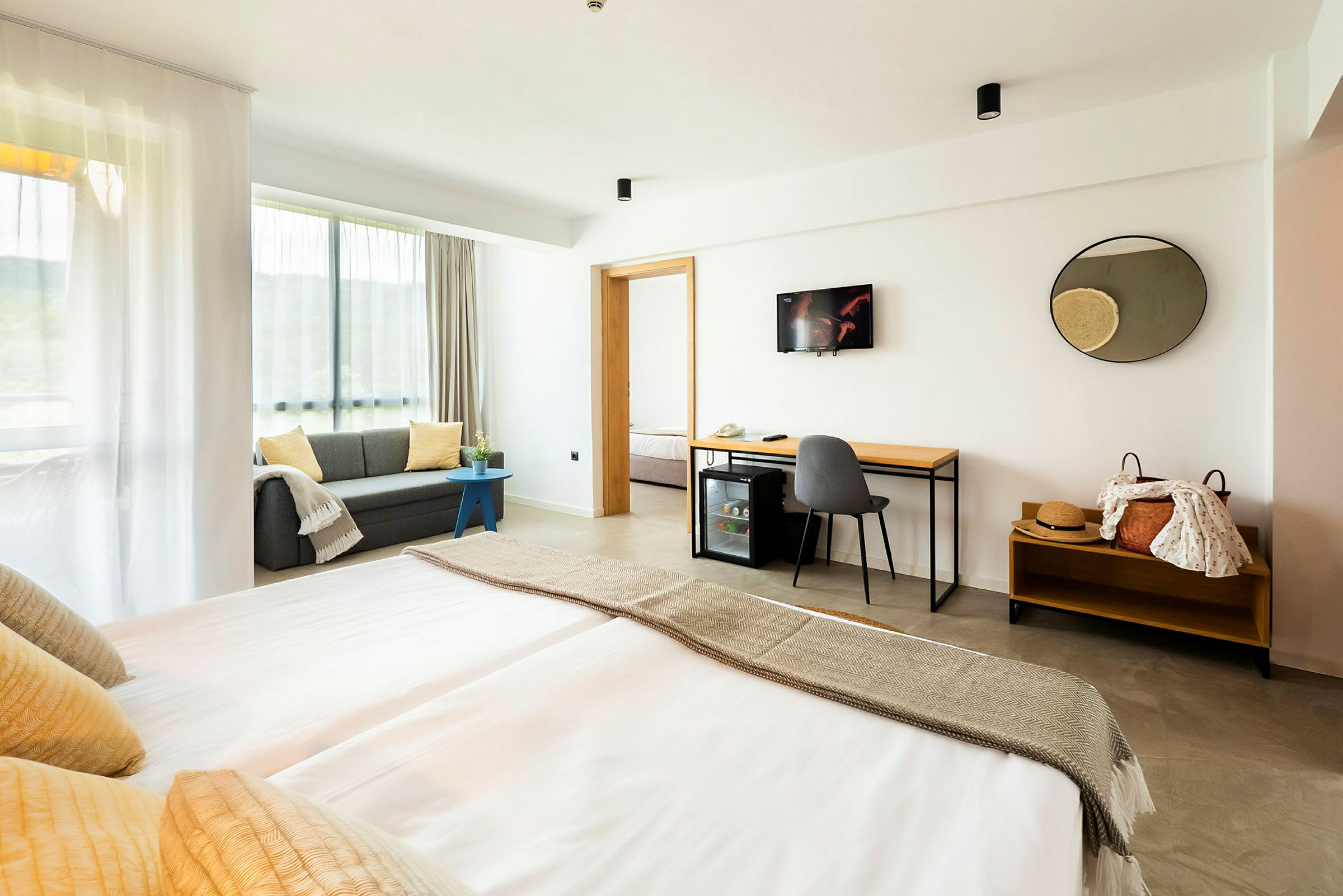 Moderne hotelværelse med dobbeltseng, sofa og skrivebord. (AI-genereret tekst)