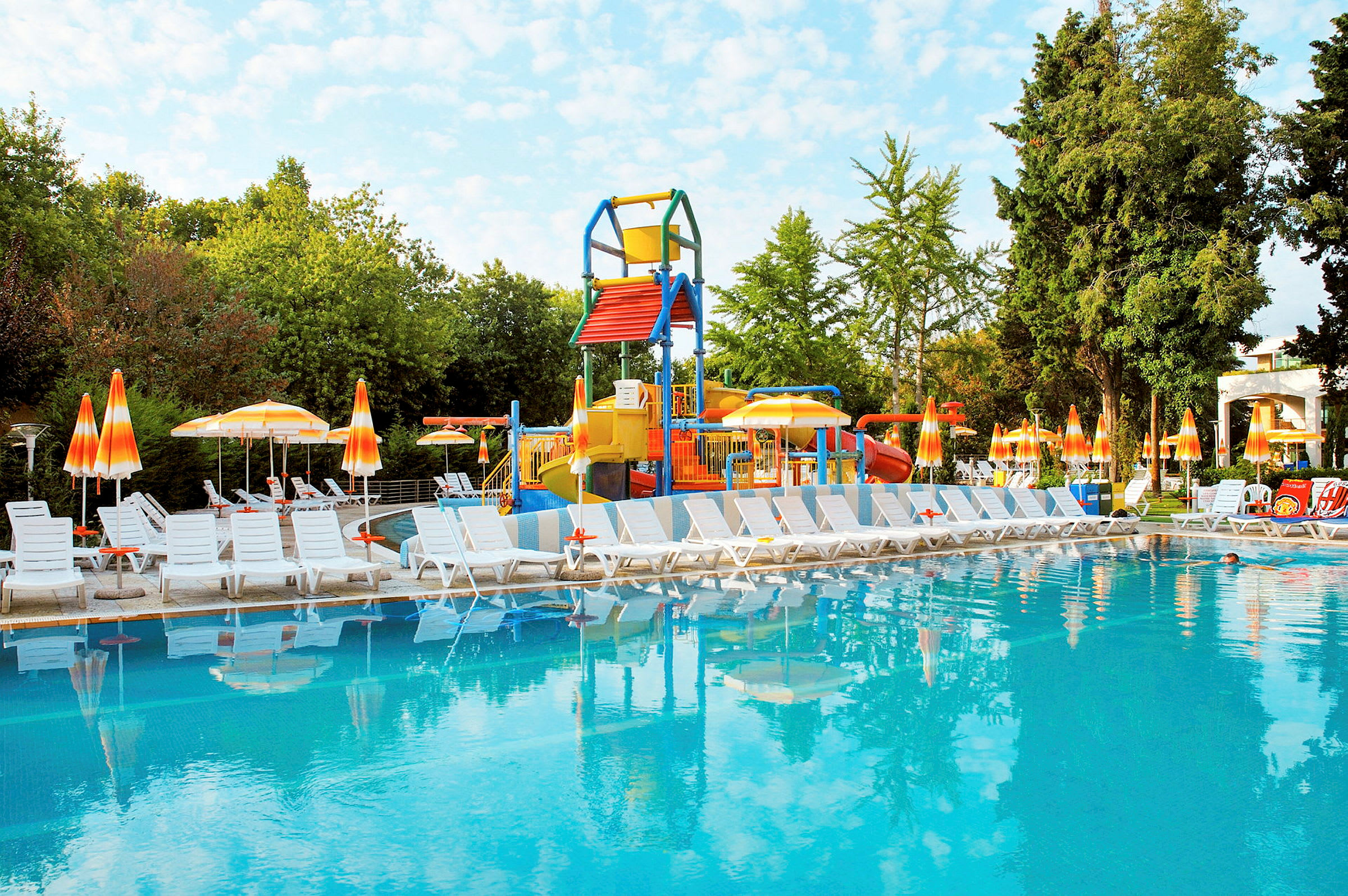 Pool med solsenge og legeplads i baggrunden. (AI-genereret tekst)