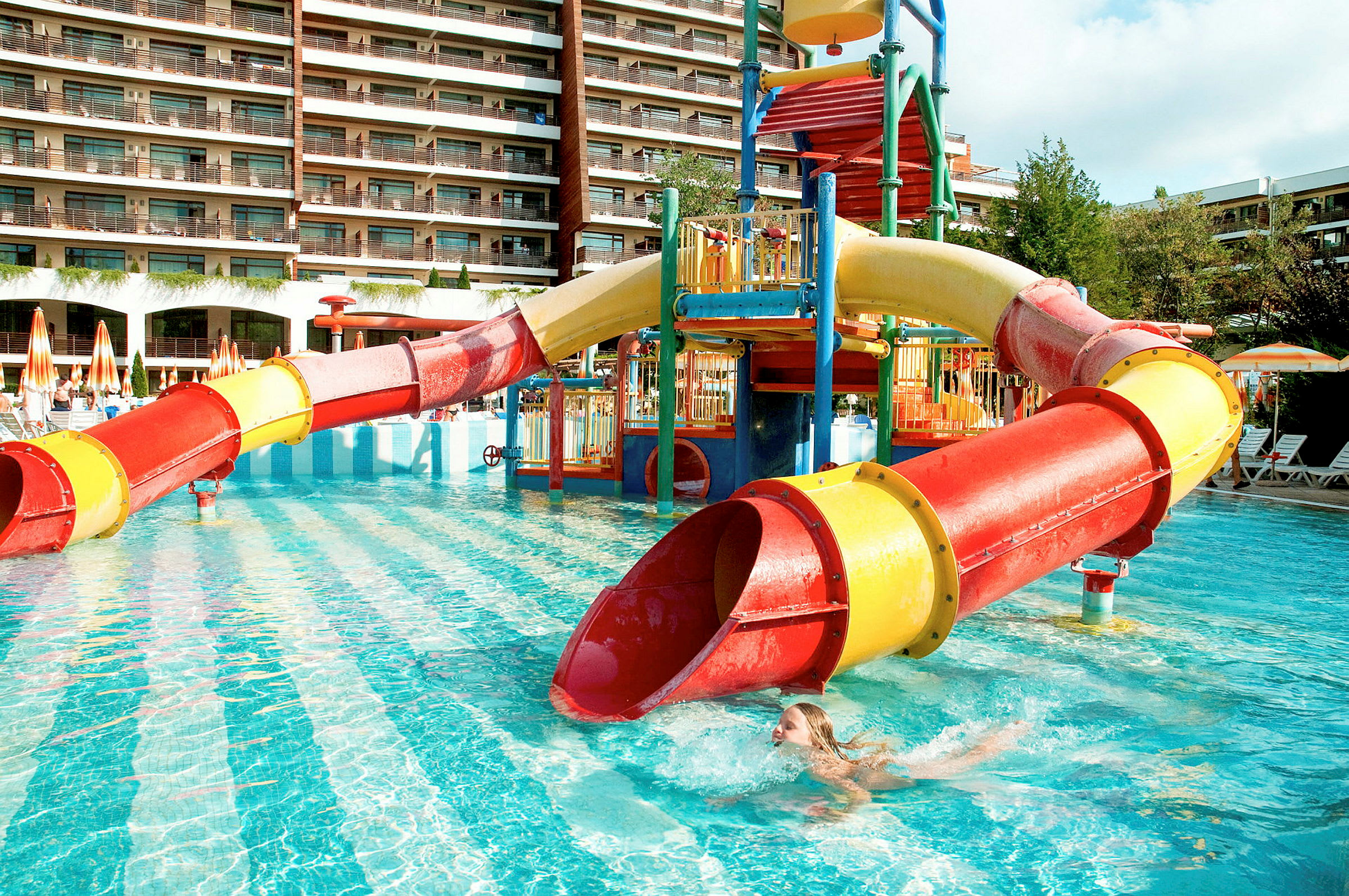 Vandrutsjebane ved poolområde med hotel i baggrunden. (AI-genereret tekst)