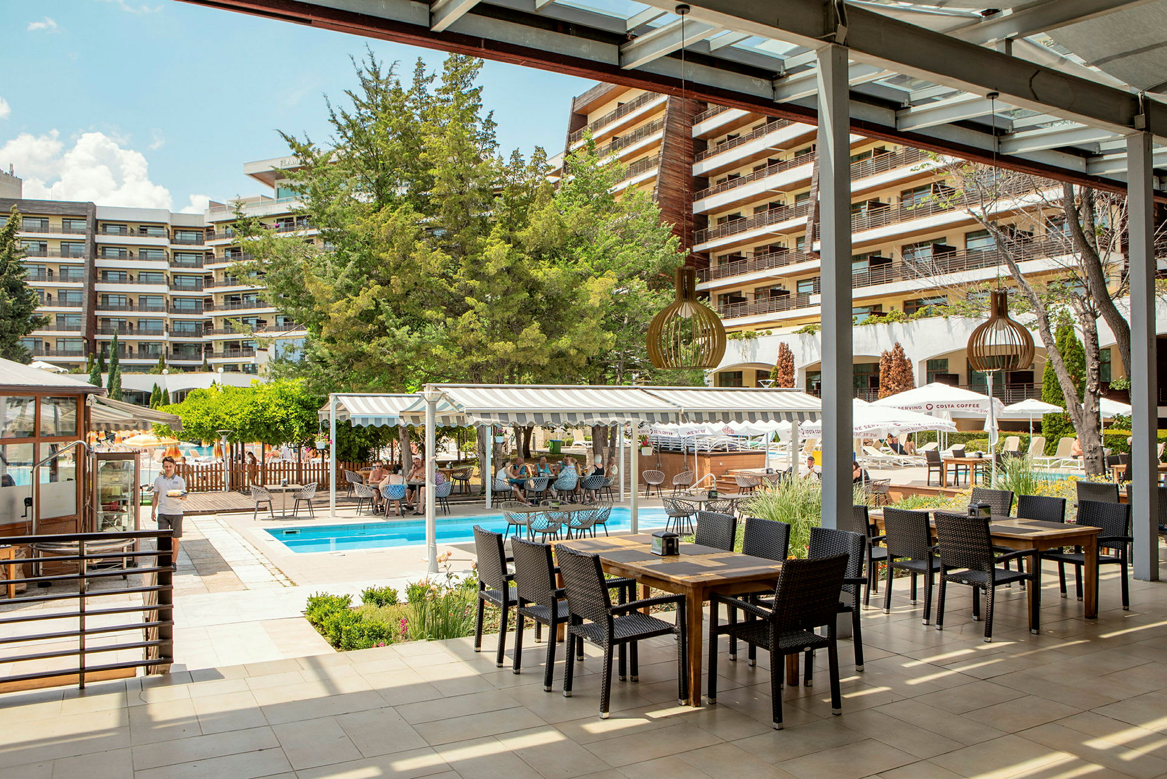 Udendørsområde ved hotel med en pool og siddepladser under tag. (AI-genereret tekst)