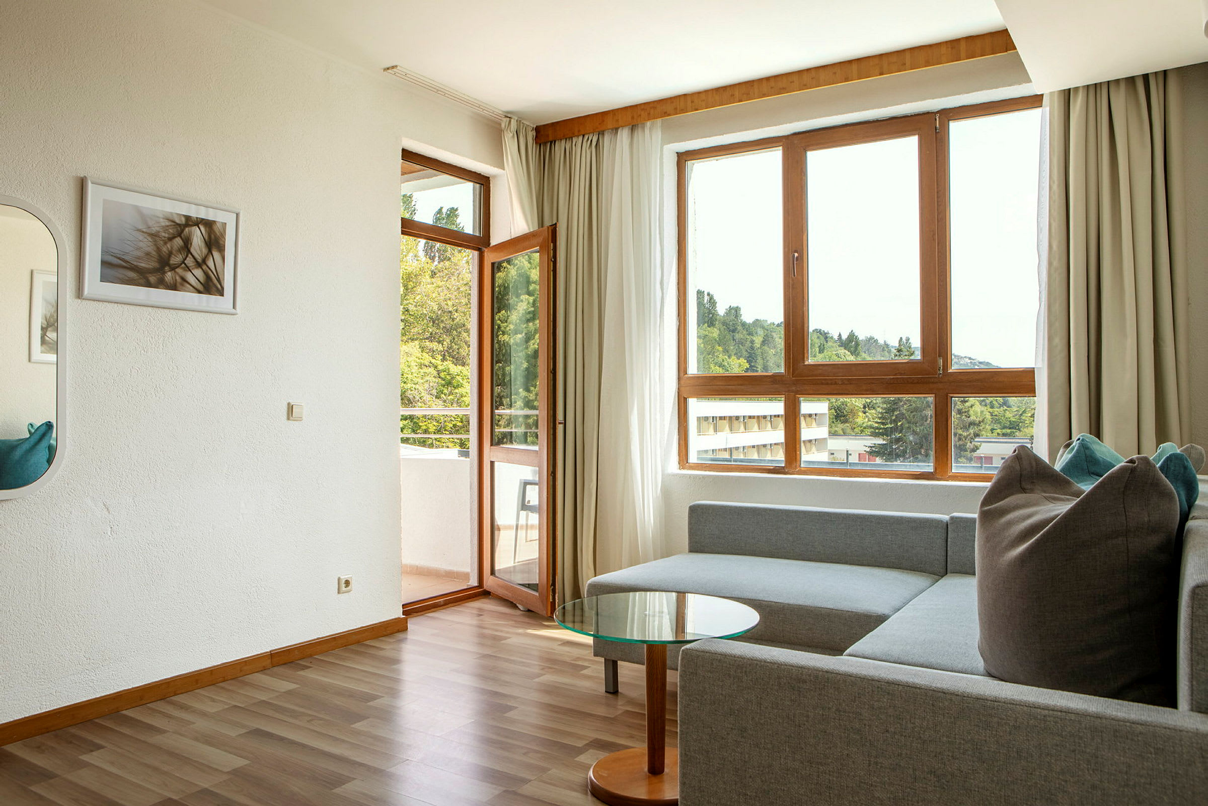 Moderne stue med sofa, glasbord og store vinduer med udsigt. (AI-genereret tekst)