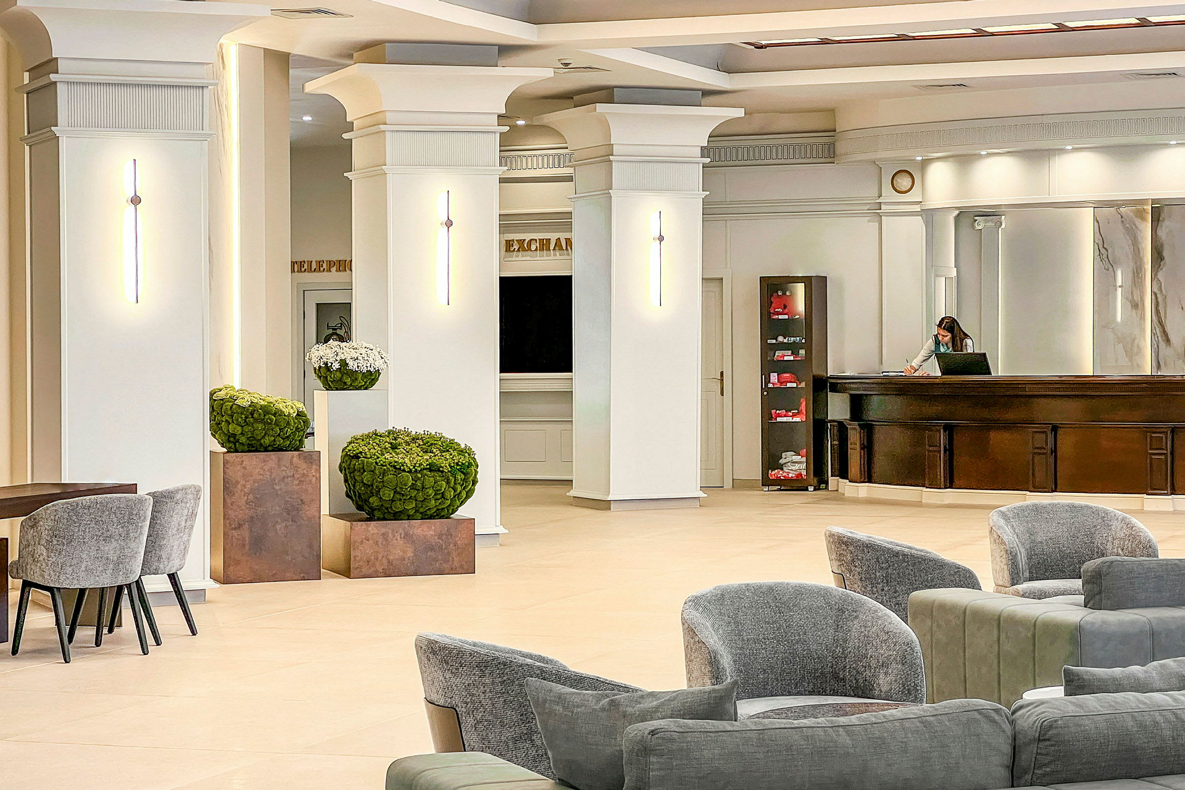 Lys og rummelig hotellobby med moderne møbler og stilfulde vægdetaljer. (AI-genereret tekst)