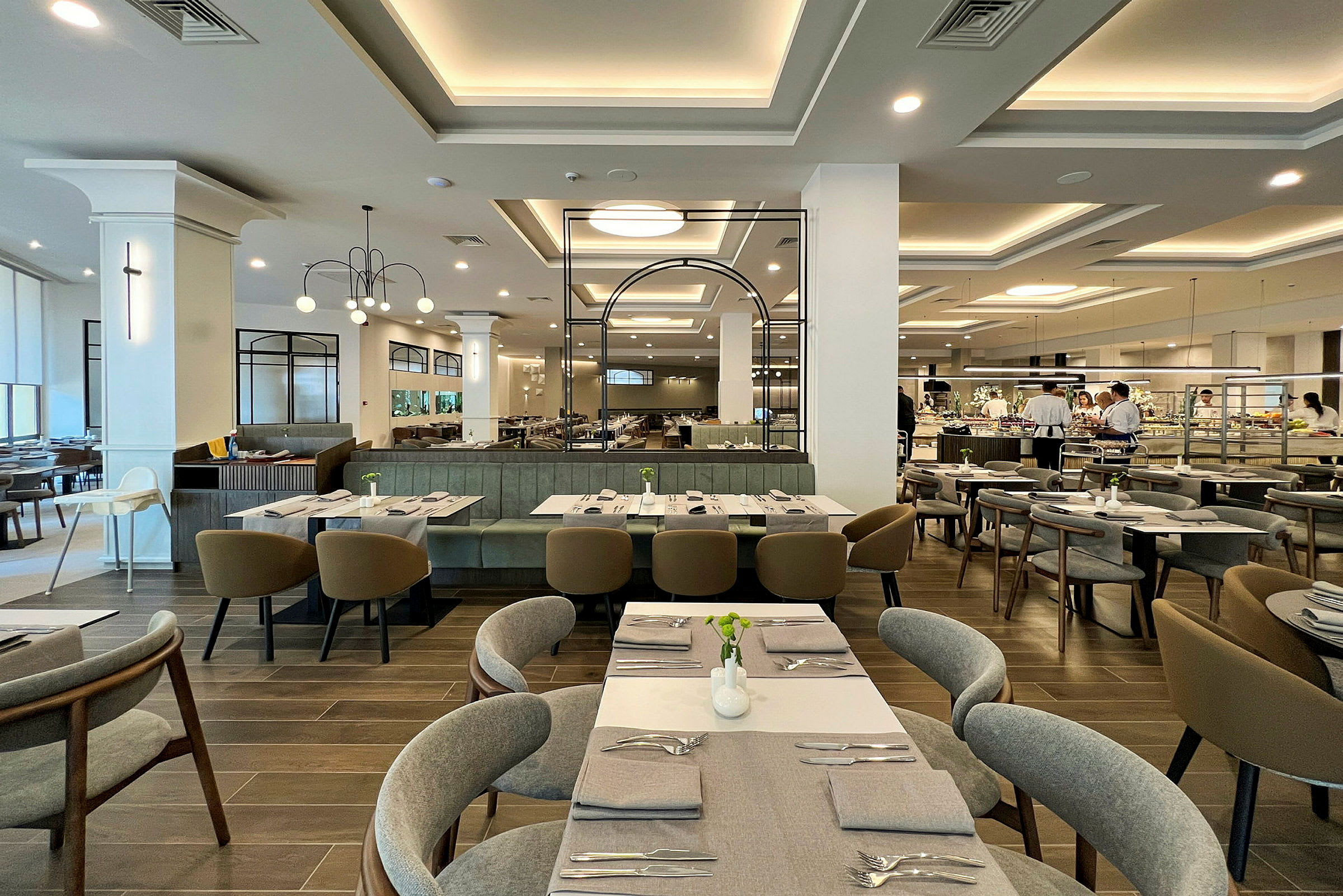 Et moderne restaurantområde med borde og stole samt en madbuffet i baggrunden. (AI-genereret tekst)