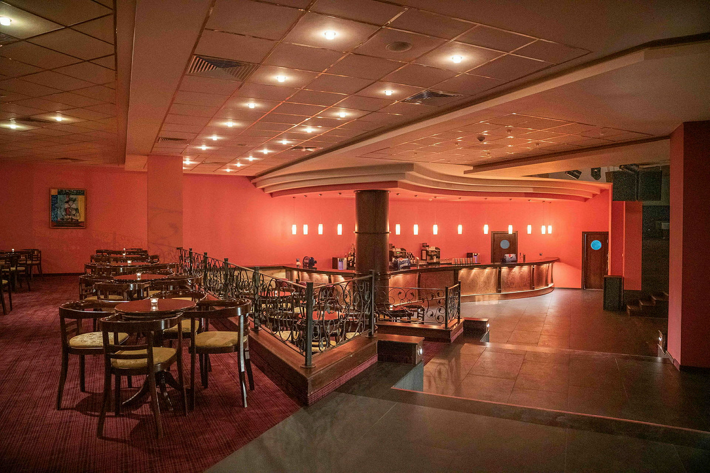 En restaurant med borde og stole samt en bar med glødende lamper i baggrunden. (AI-genereret tekst)