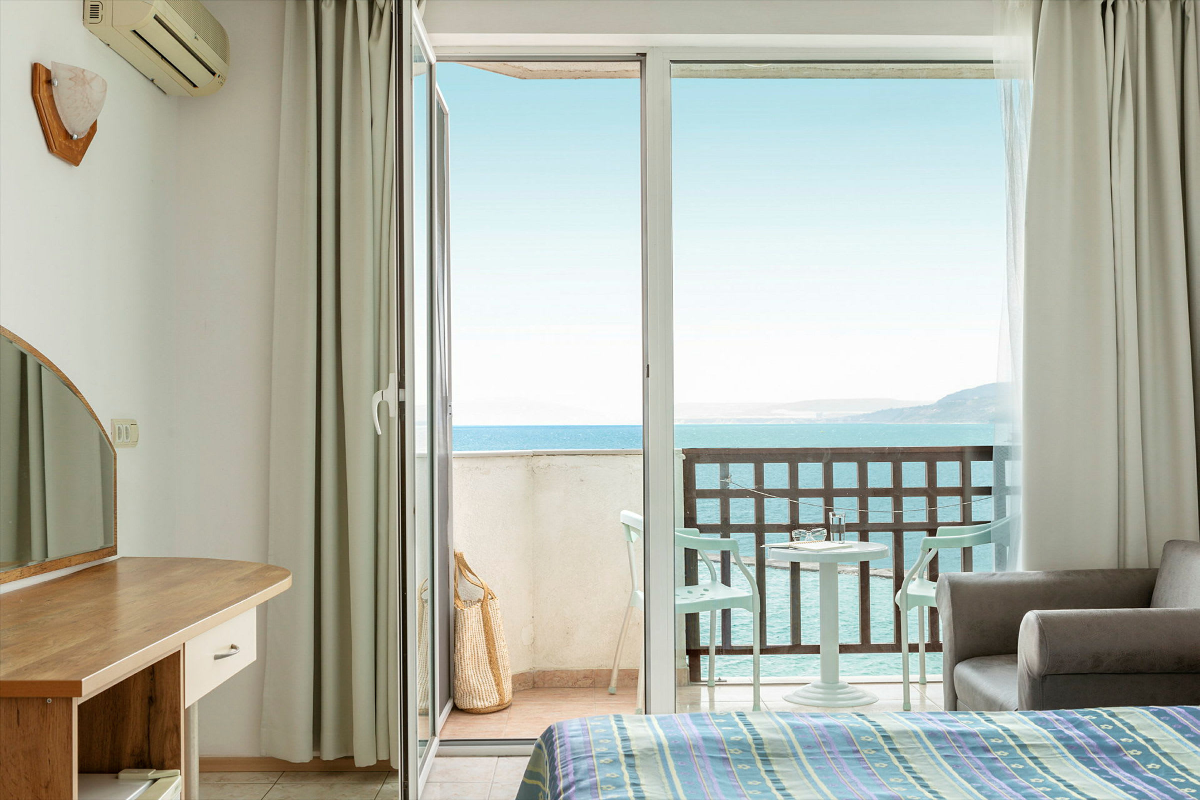 Hotelværelse med åben balkon dør og havudsigt. (AI-genereret tekst)