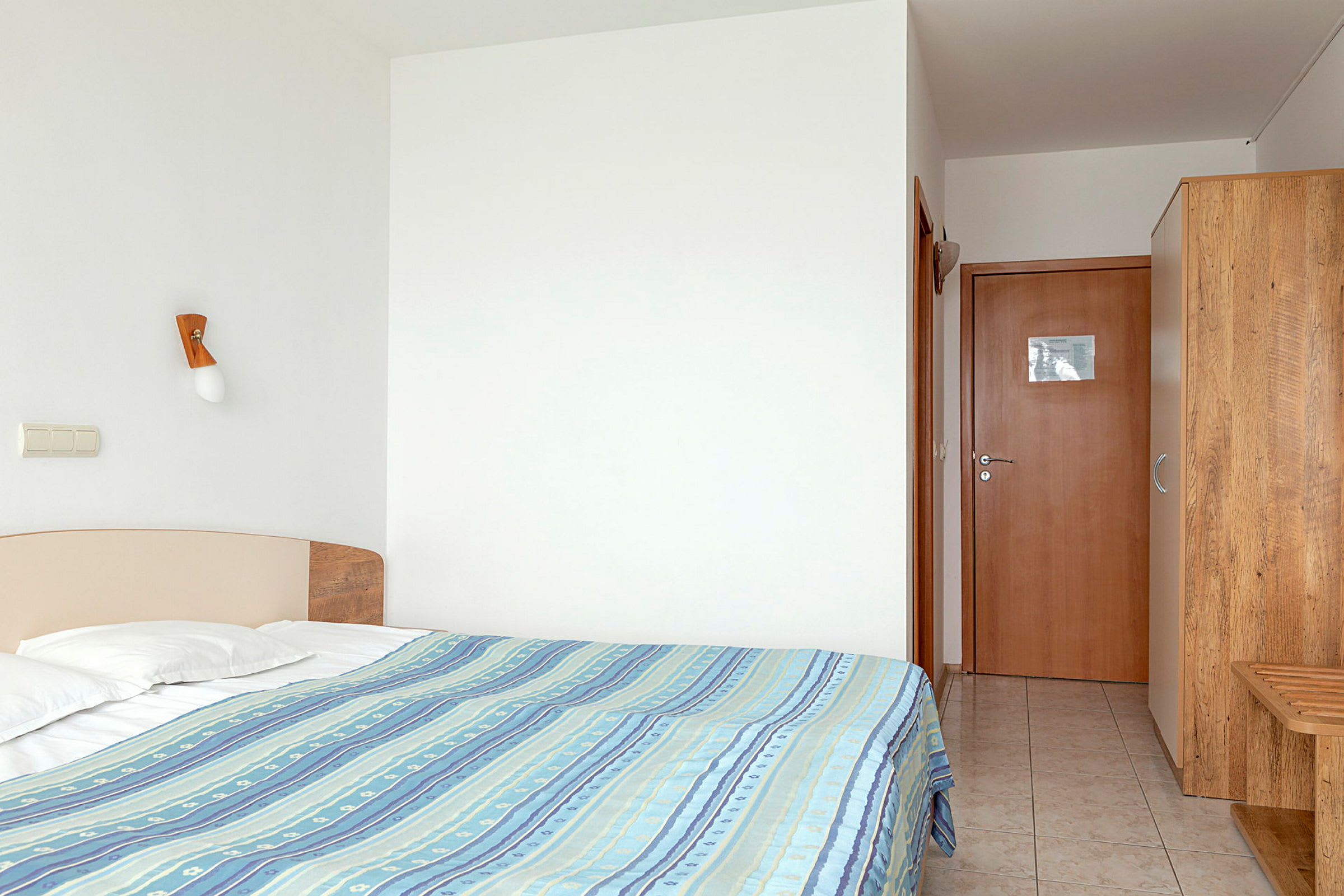 Hotelværelse med seng, garderobe og døråbning. (AI-genereret tekst)