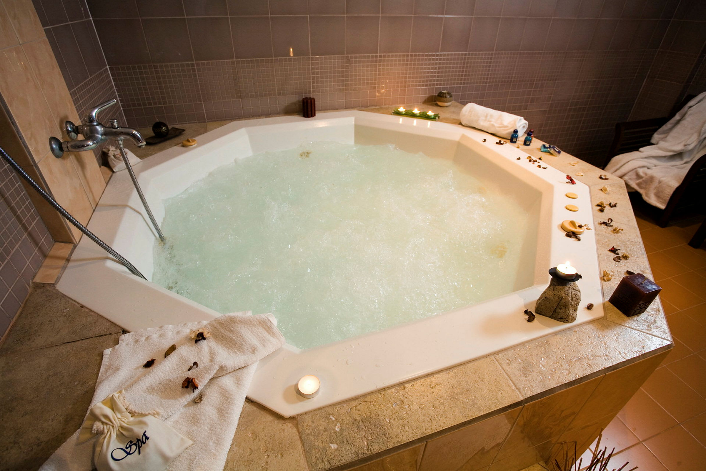 Indendørs jacuzzi med boblende vand, omgivet af dekoration og stearinlys. (AI-genereret tekst)