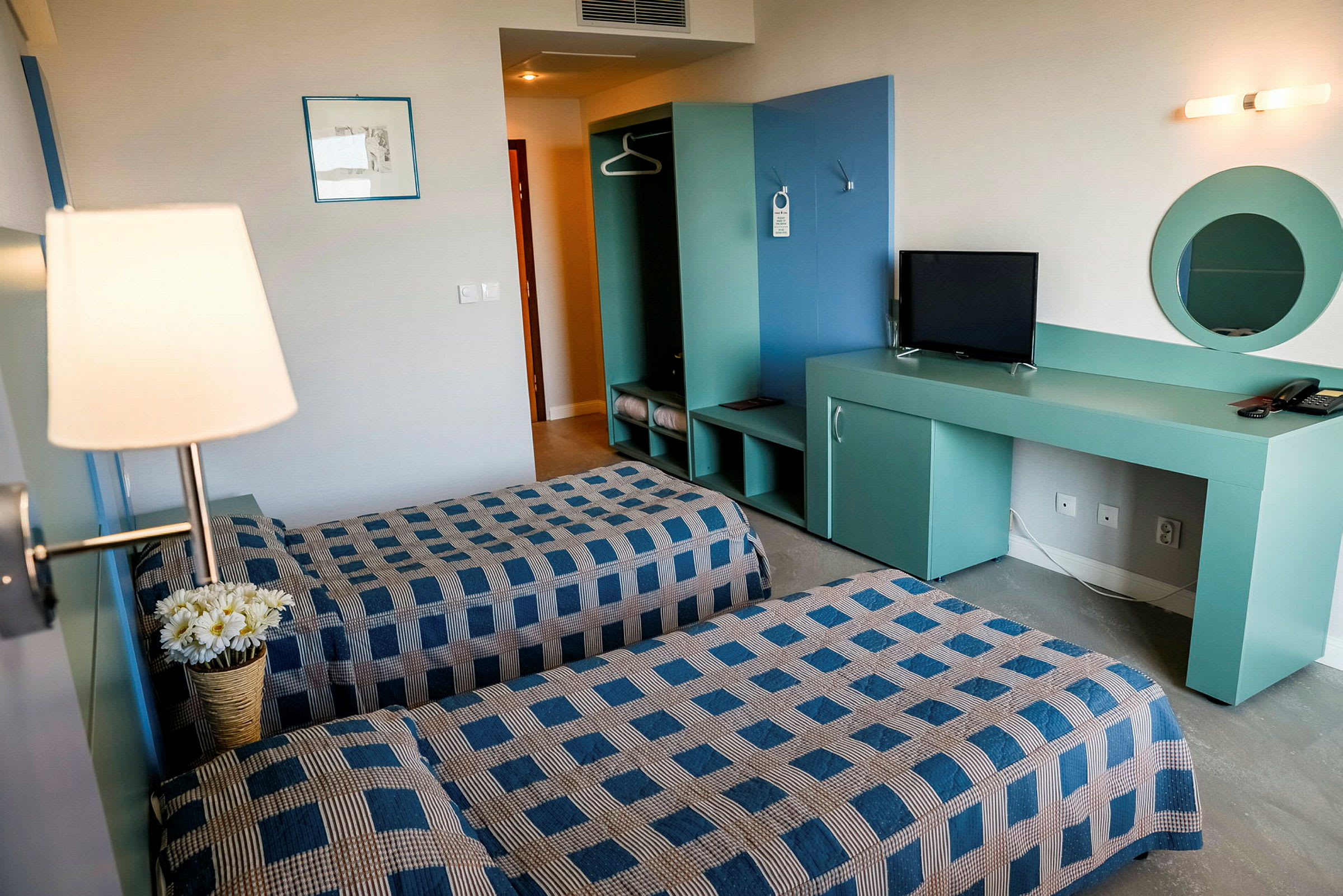Et hotelværelse med to enkeltsenge, tv og garderobe. (AI-genereret tekst)