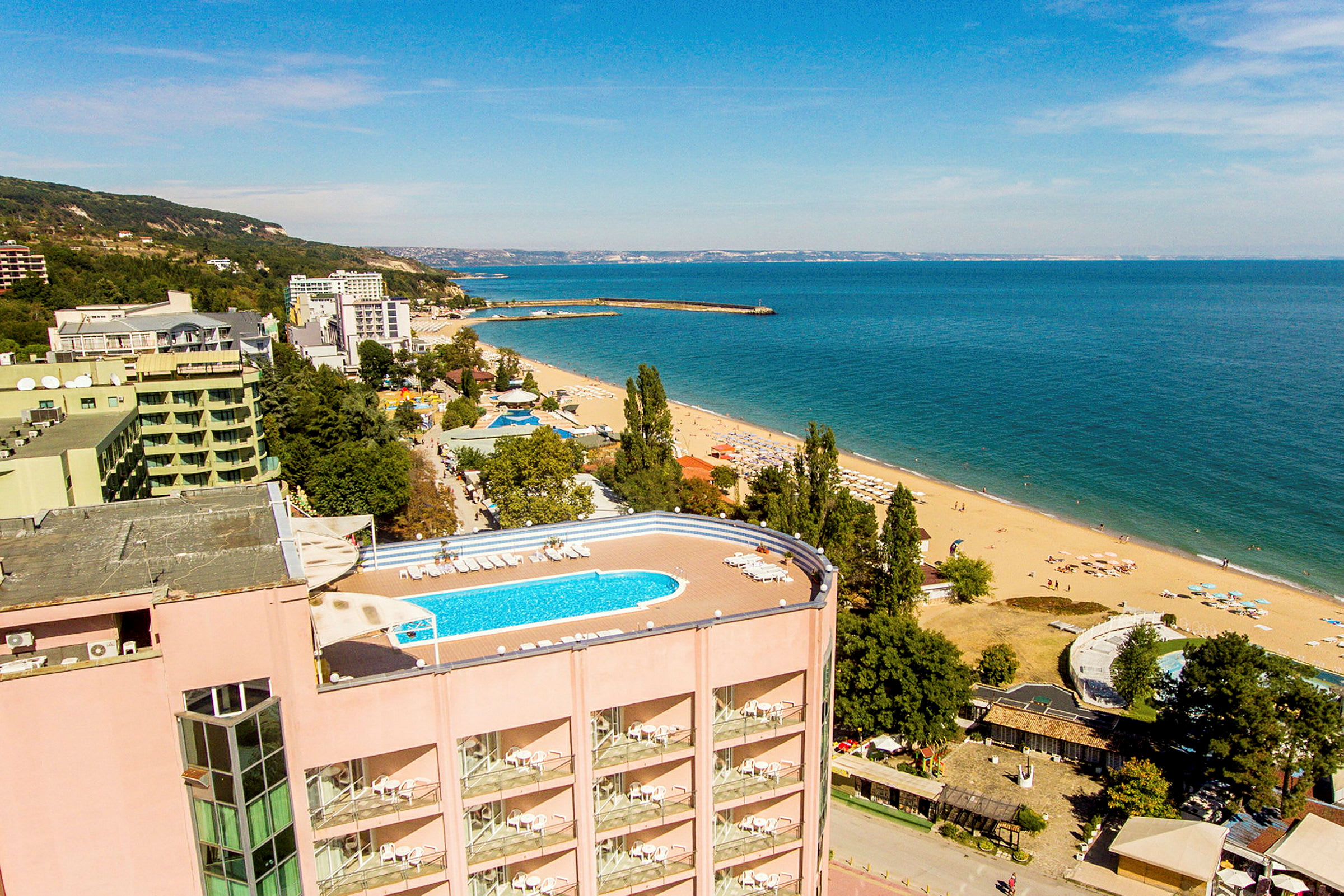 Udsigt over en strand med hotel og en pool. (AI-genereret tekst)