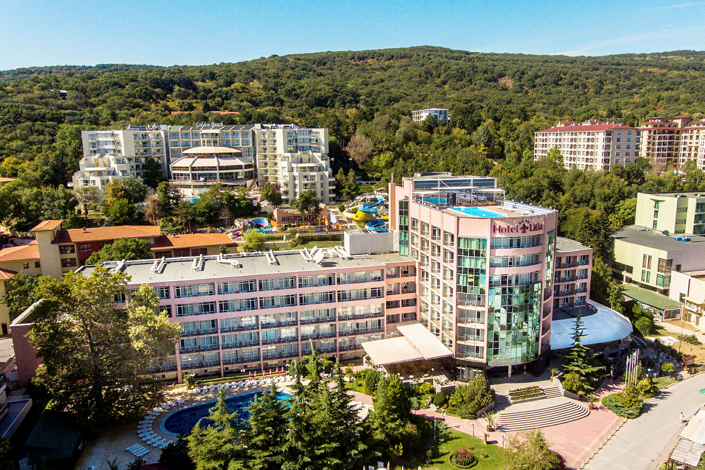 Udsigt over et hotelkompleks med pool og omkringliggende grønt. (AI-genereret tekst)