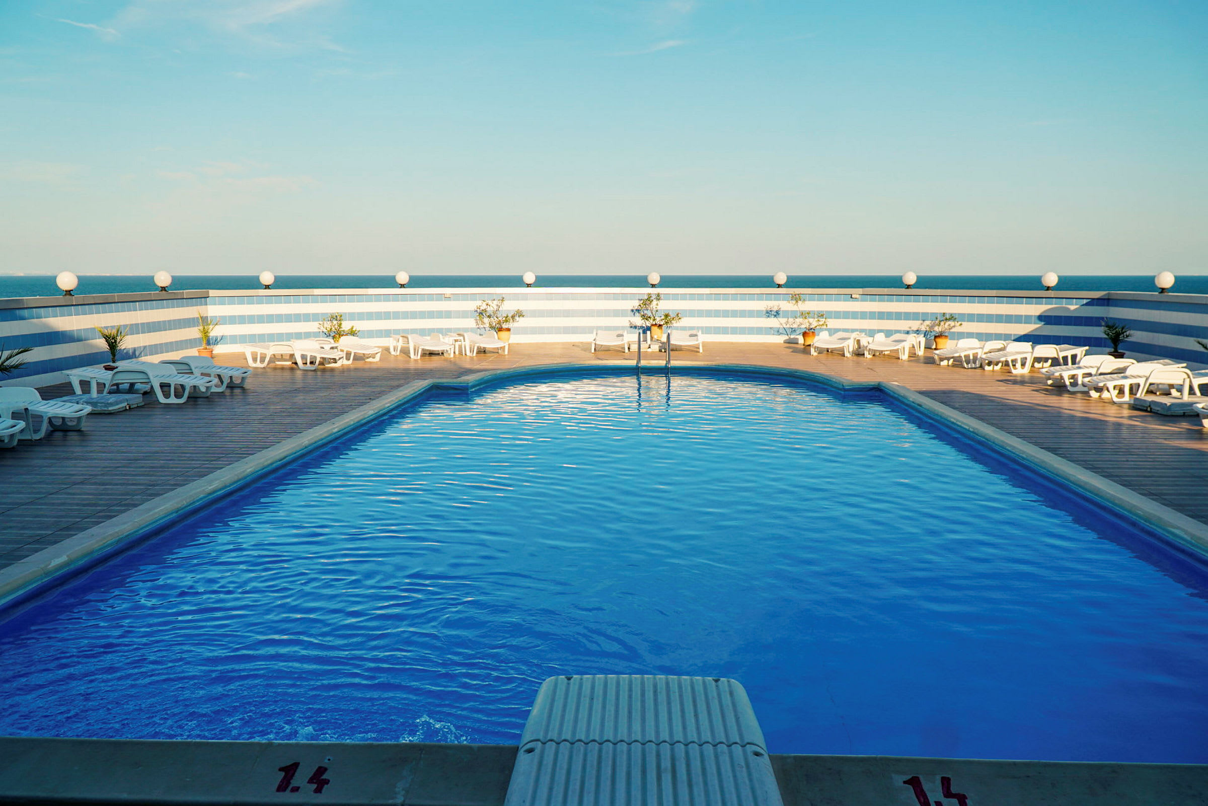 Pool med liggestole og blå himmel. (AI-genereret tekst)