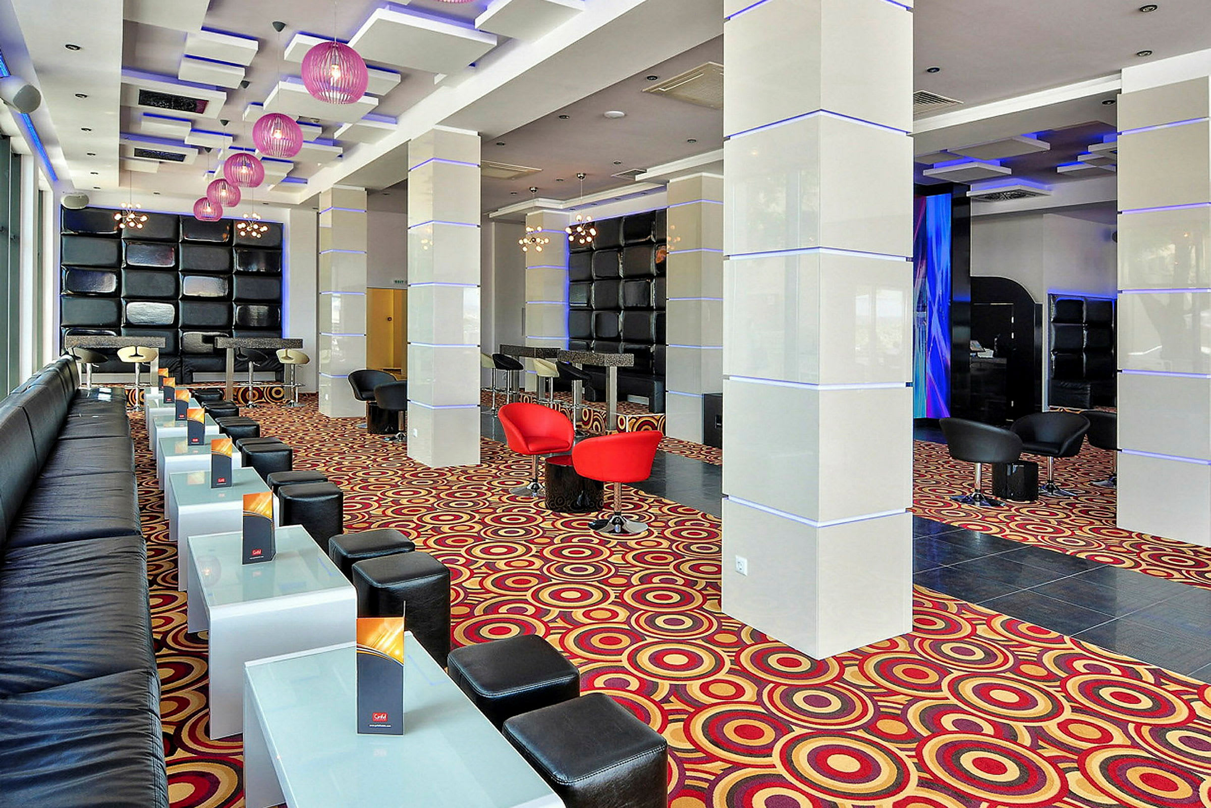 Moderne lounge med siddepladser, glasborde og farvestrålende gulvtæppe. (AI-genereret tekst)