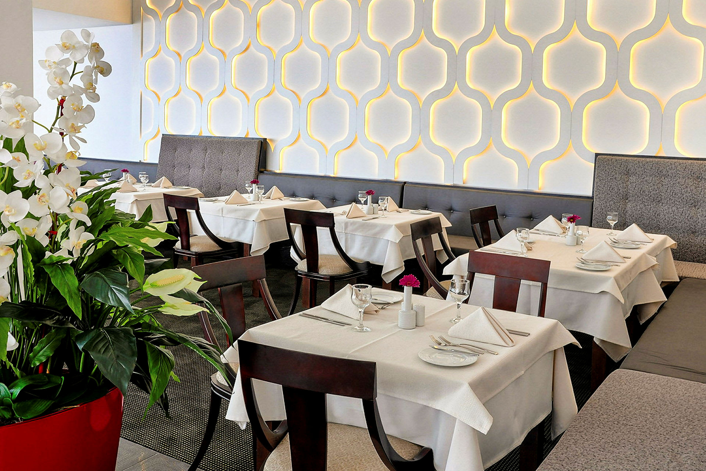 Elegant restaurant med opdækkede borde og dekorative hvide blomster. (AI-genereret tekst)