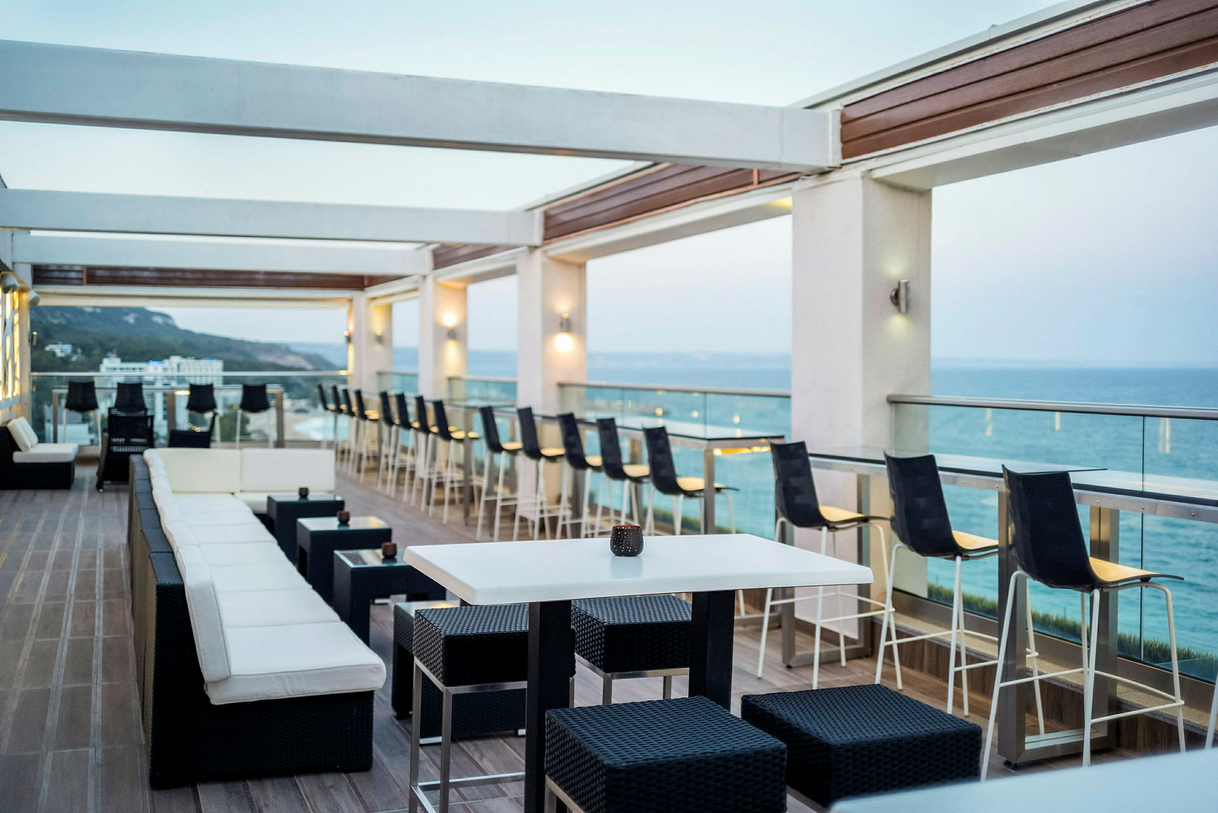 En åben terrasse med siddepladser og udsigt over havet. (AI-genereret tekst)