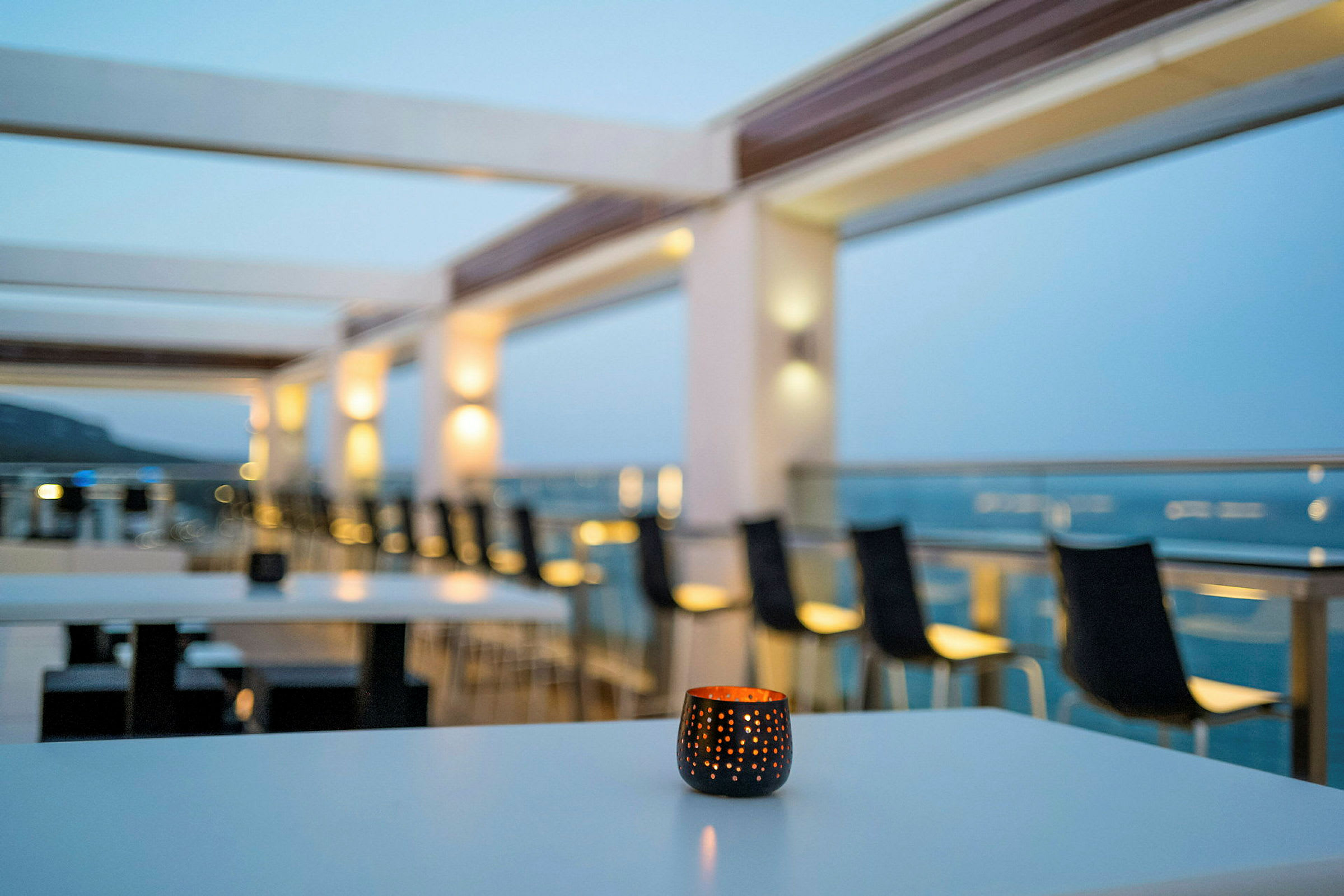 Udsigt over en terrasse med borde og stole, med et lys foran. (AI-genereret tekst)
