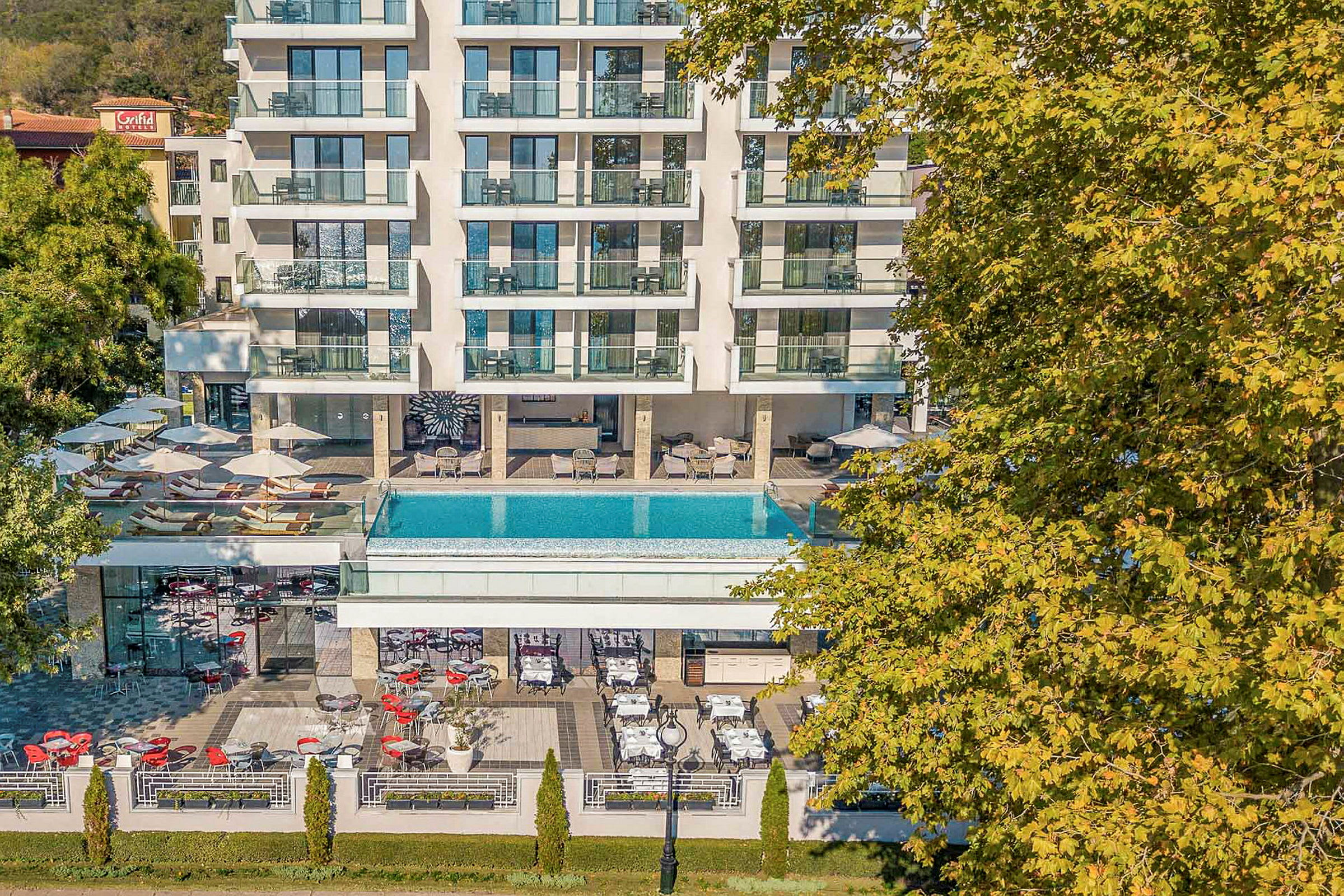 Flerbygningkompleks med udendørs pool og terrasse. (AI-genereret tekst)