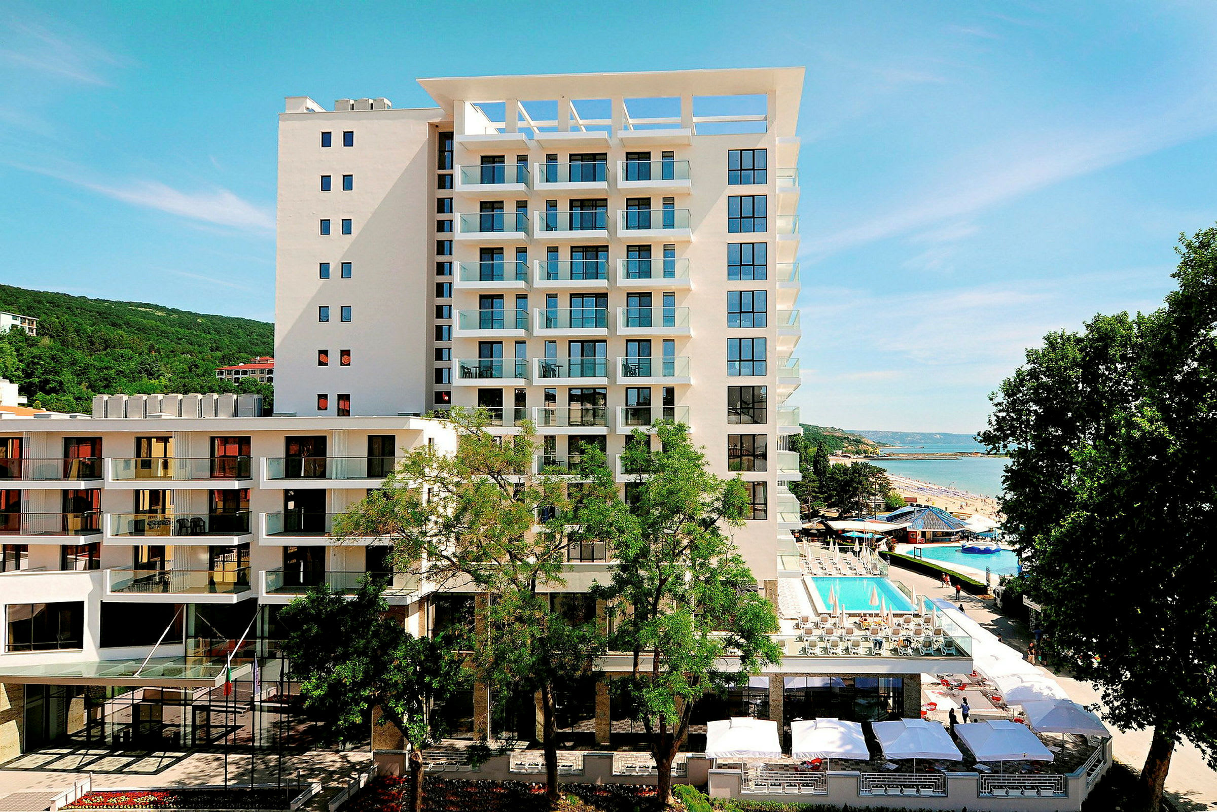 Billede af en moderne hotelbygning med en pool på sit område, beliggende ved havet. (AI-genereret tekst)