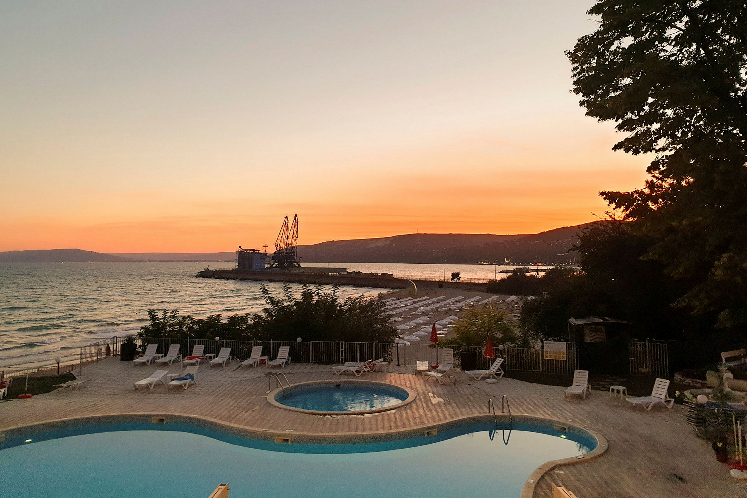 Solnedgang ved havet med en pool i forgrunden. (AI-genereret tekst)