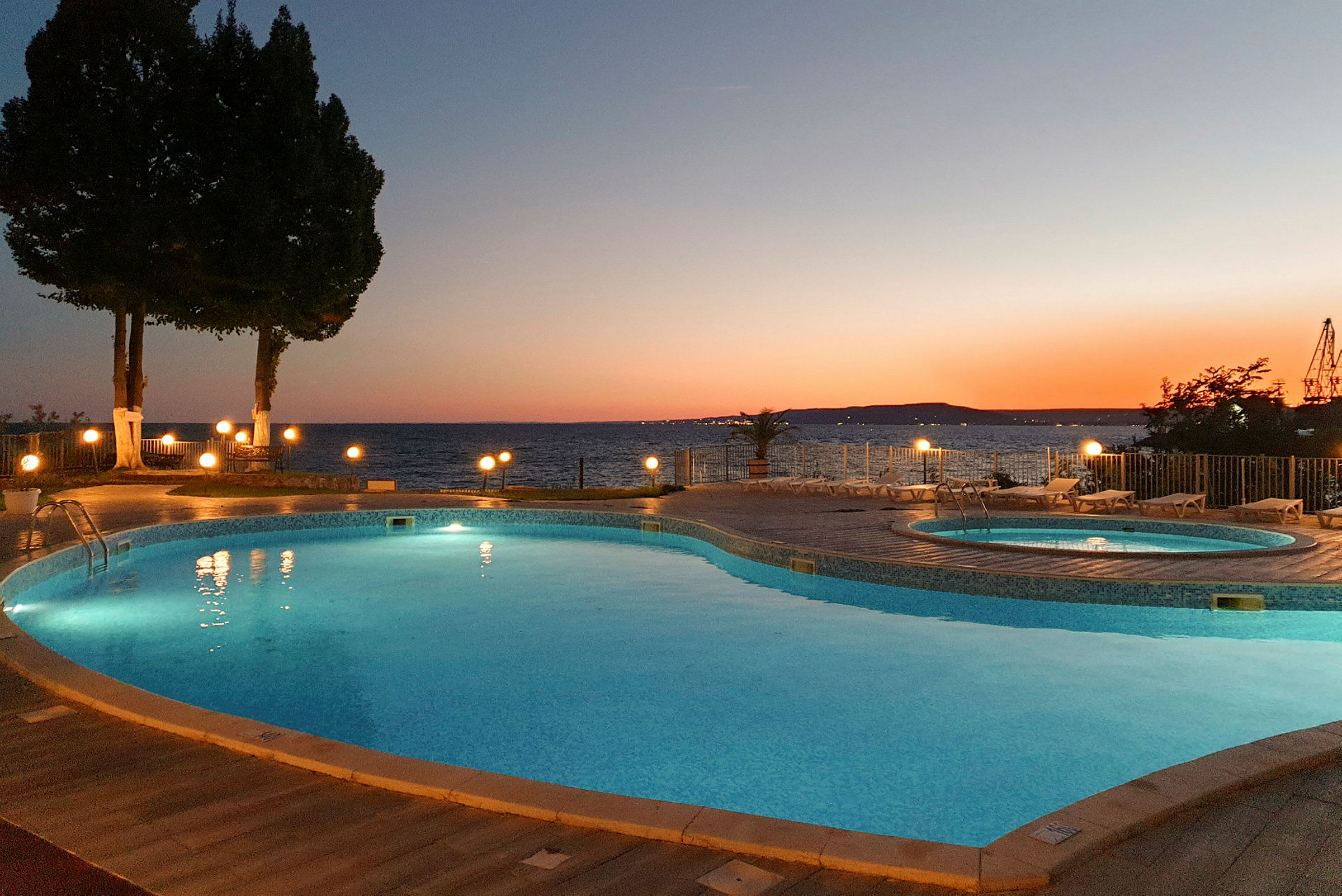En swimmingpool med udsigt over havet ved solnedgang. (AI-genereret tekst)
