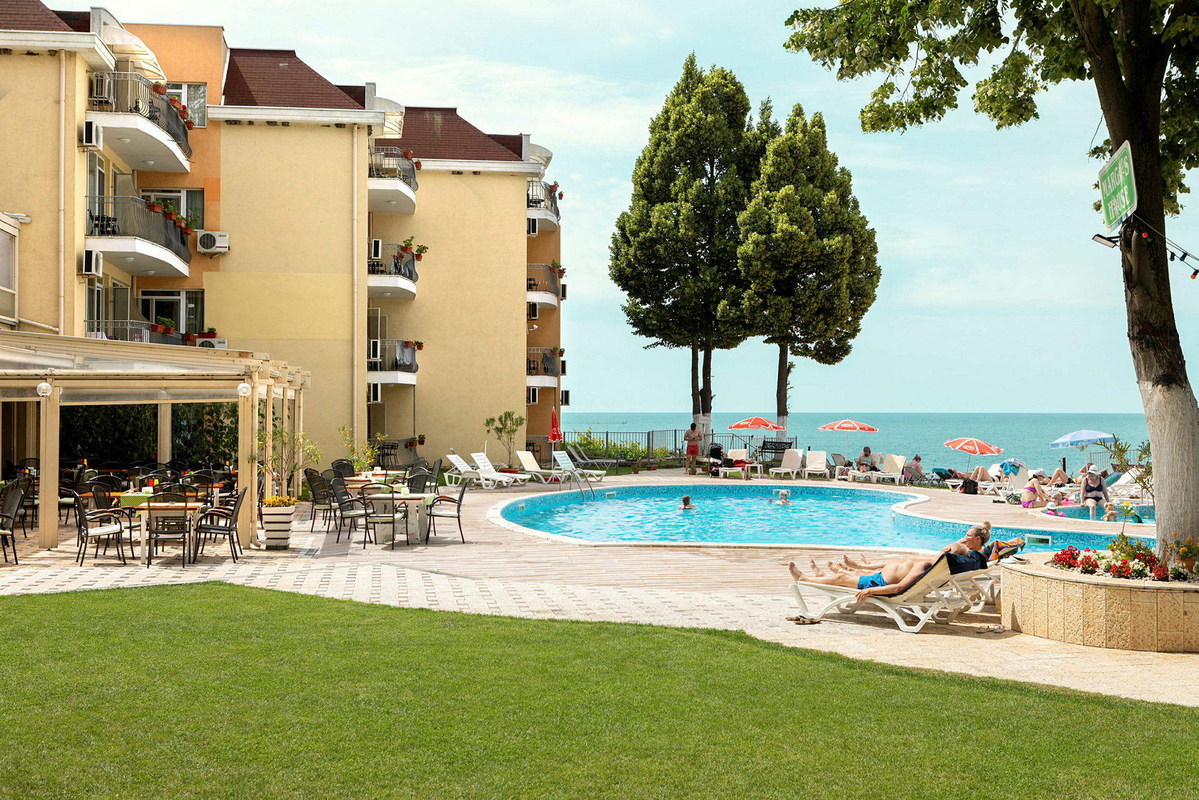 Poolområde ved hotel med liggestole, parasoller og udsigt over havet. (AI-genereret tekst)