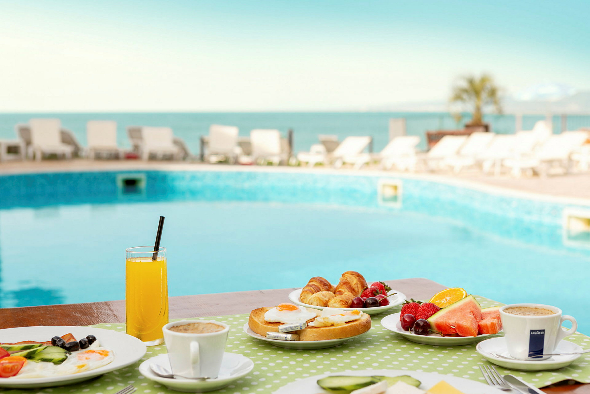 Morgenmad med brød, frugt og kaffe ved en pool. (AI-genereret tekst)