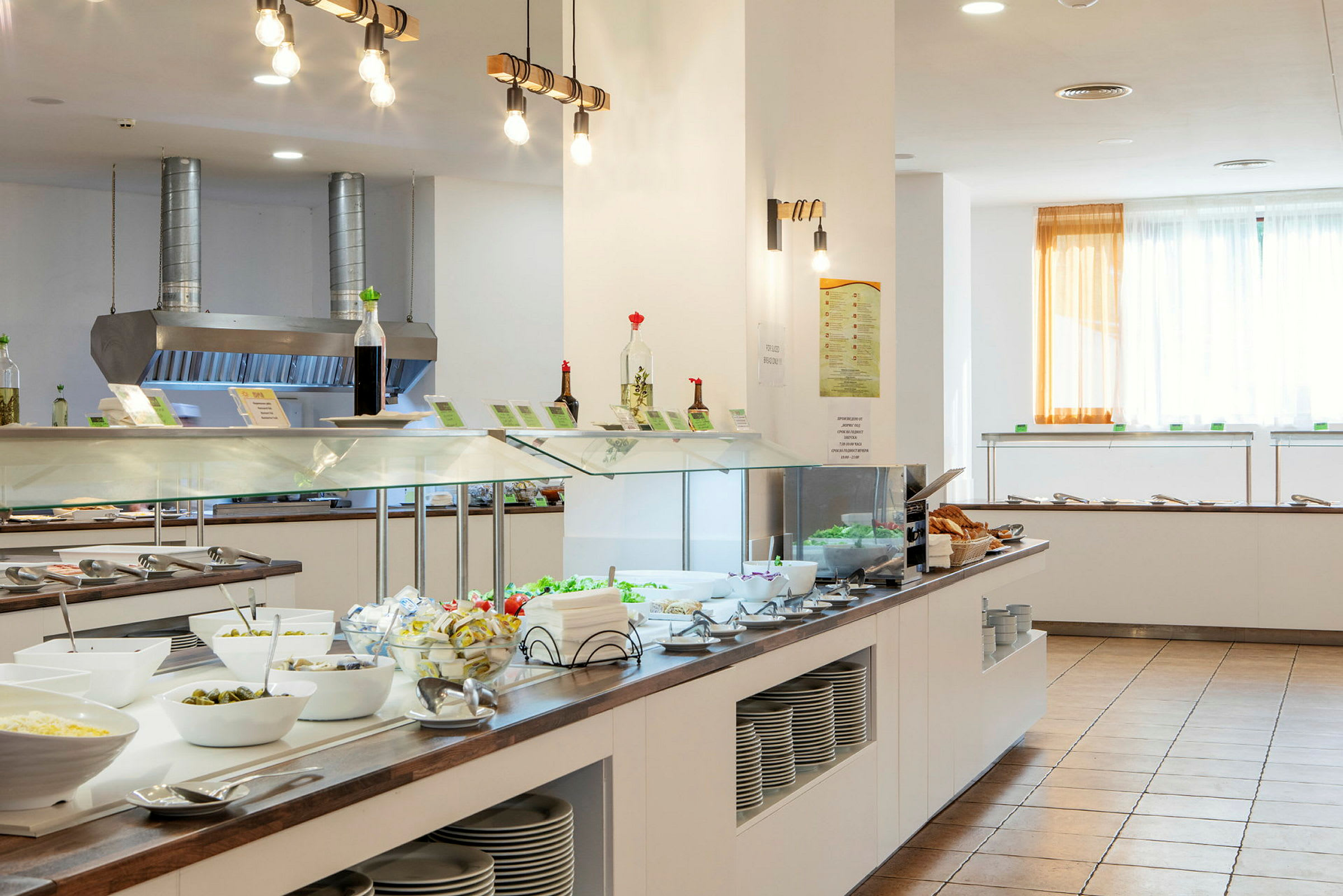 Billede af en buffet med salater, tilbehør og skåle i en lys spisesal. (AI-genereret tekst)