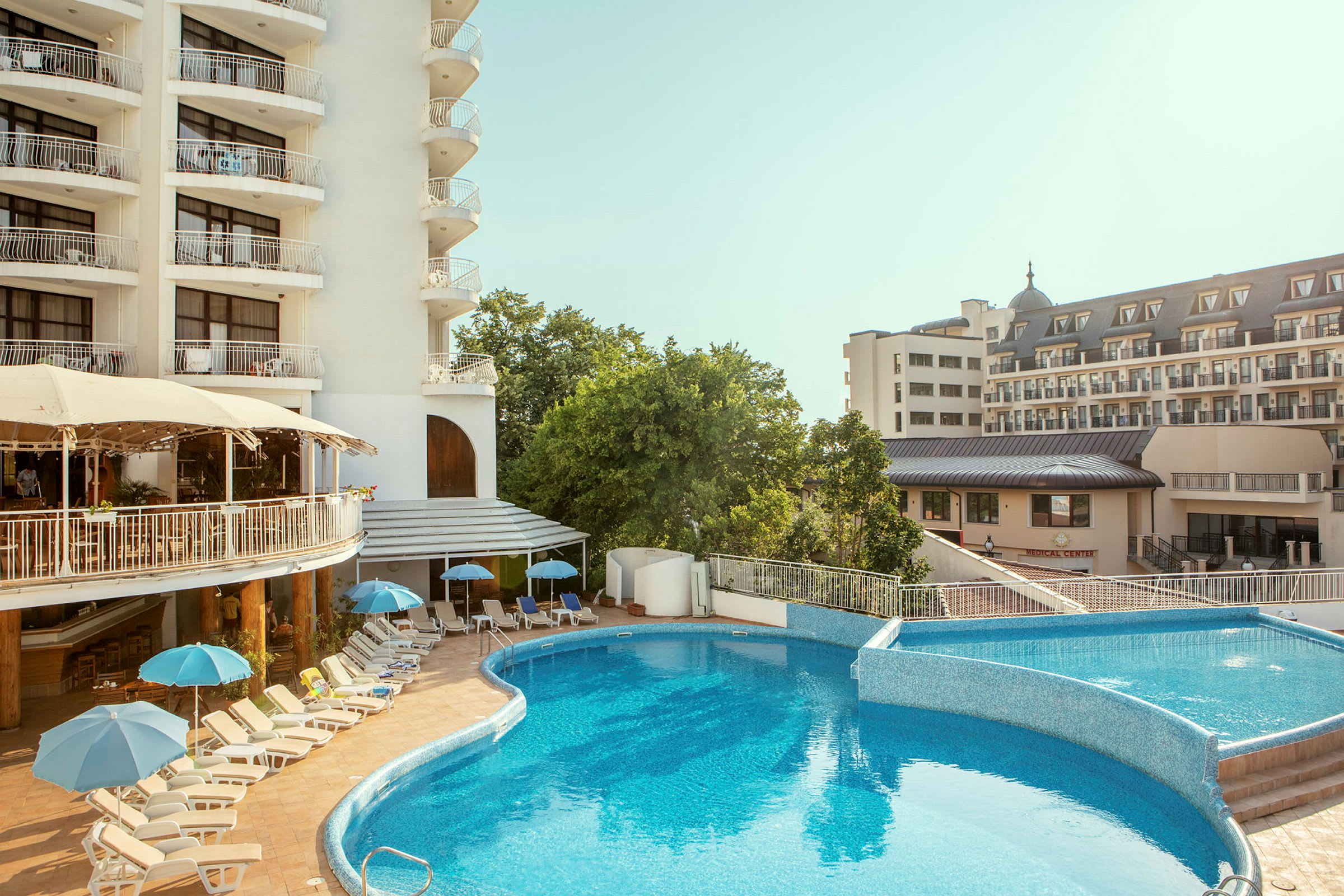 Poolområde med solsenge og parasoller ved et hotel. (AI-genereret tekst)