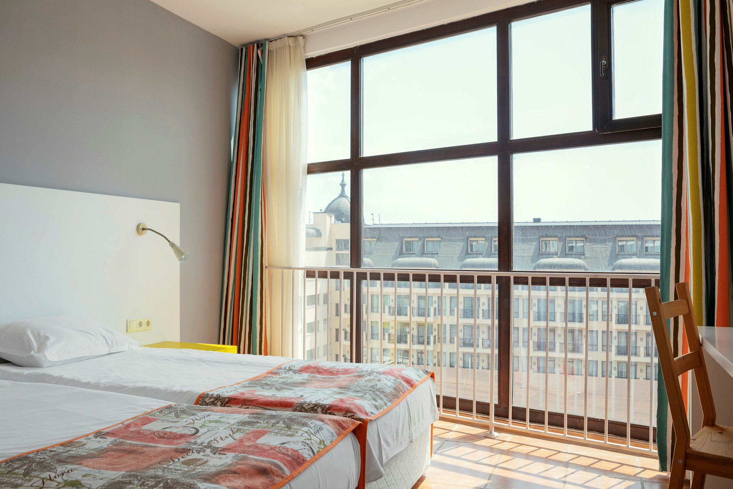 Hotelværelse med to enkeltsenge og stort vindue mod byudsigt. (AI-genereret tekst)