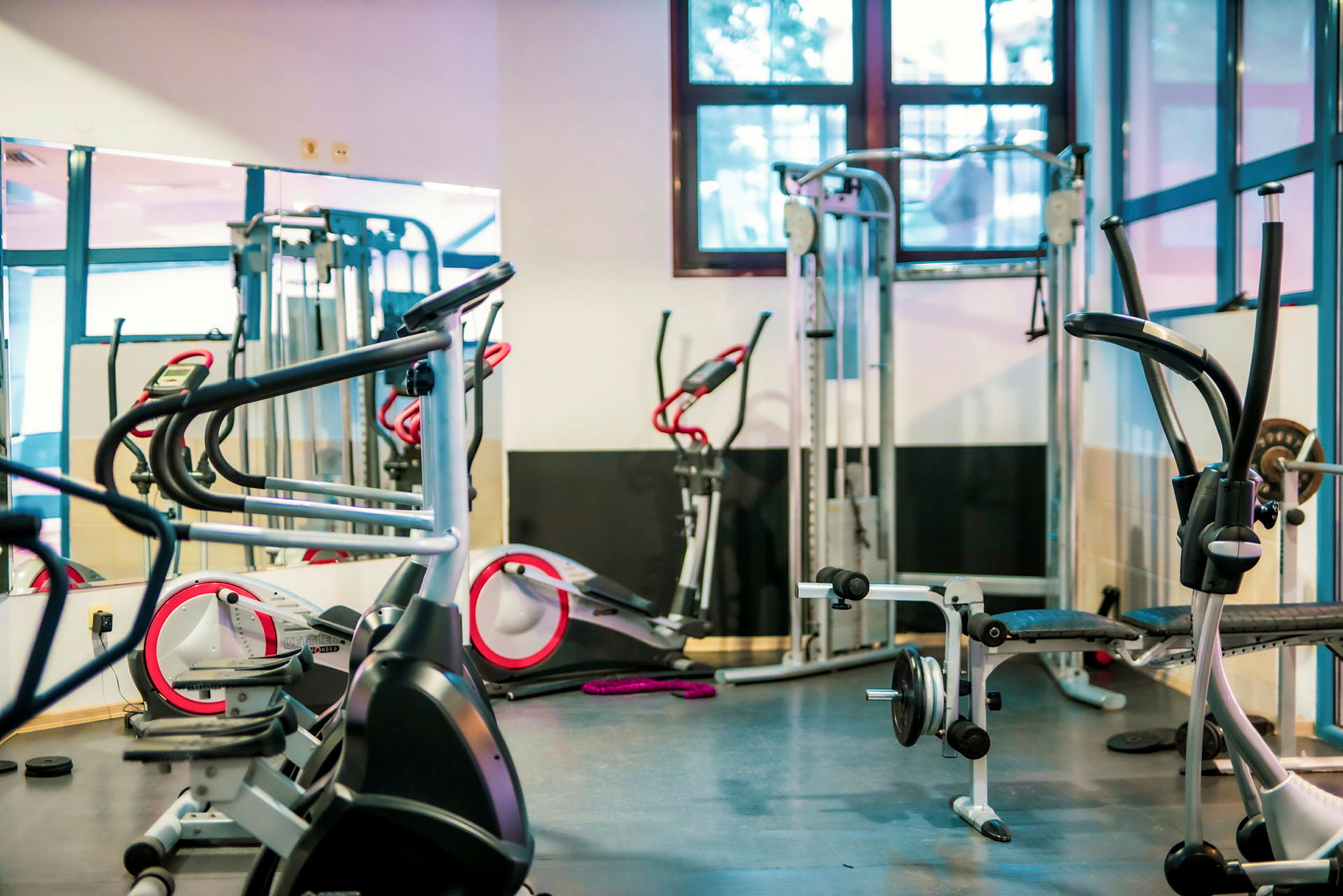 Billede af et træningsrum med fitnessudstyr som motionscykler, vægtbænke og maskiner. (AI-genereret tekst)