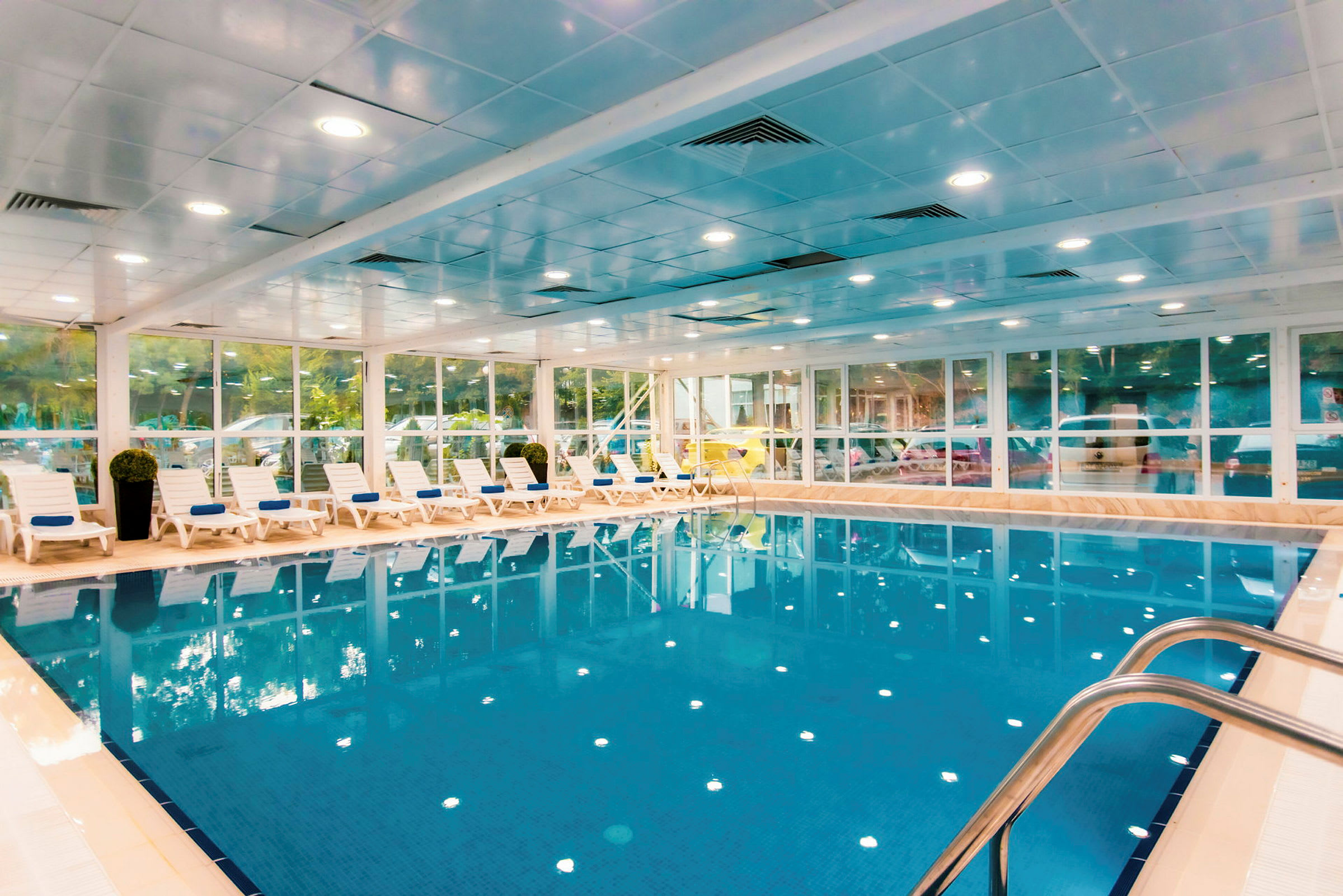 Indendørs pool med klart blåt vand og liggestole langs den ene side. (AI-genereret tekst)