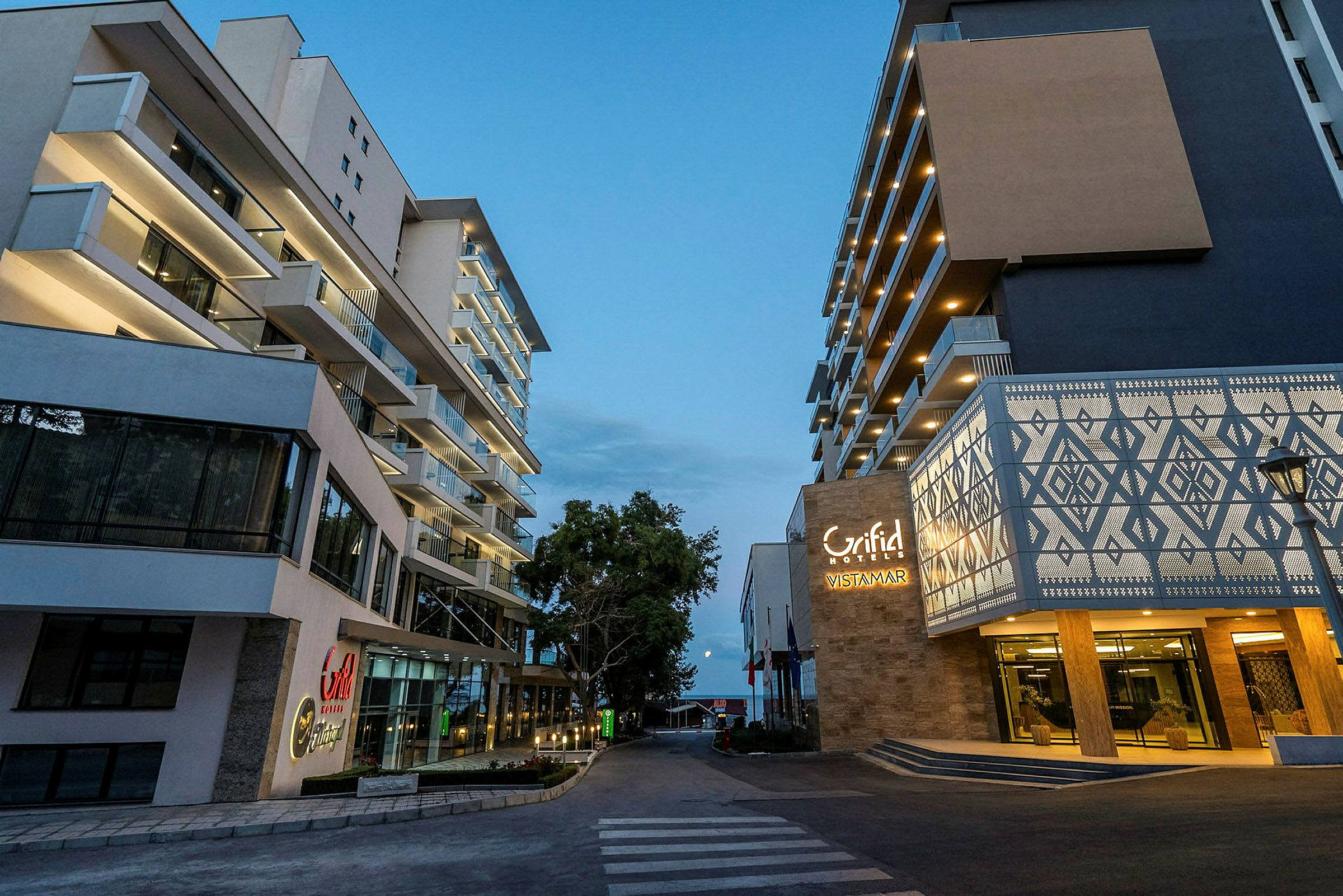 To moderne hotelbygninger ved en gangsti om aftenen. (AI-genereret tekst)